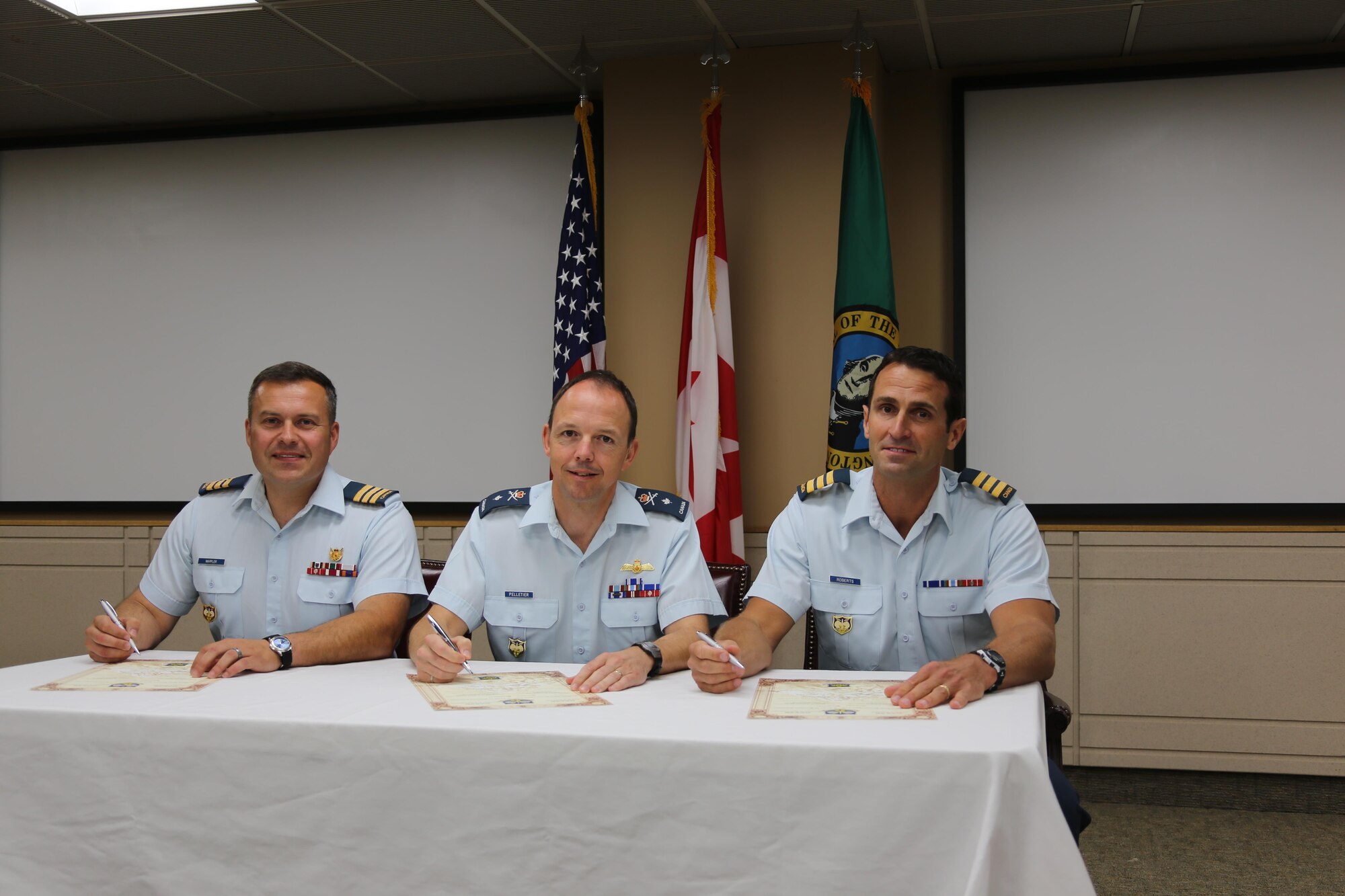 Canadian Brig. Gen. Alain Pelletier (center), deputy commander Continental U.S. North American Aerospace Defense Region-First Air Force (CONR-1AF), presides over the Canadian Detachment Joint Base Lewis-McChord change of command.  Lt. Col. Matthew Wappler (left) assumes command from the outgoing commander, Lt. Col. Mark Roberts (right), during the ceremonial signing of the change of command scrolls.   The ceremony took place July 8 at the Western Air Defense Sector, Joint Base Lewis-McChord, Wash.