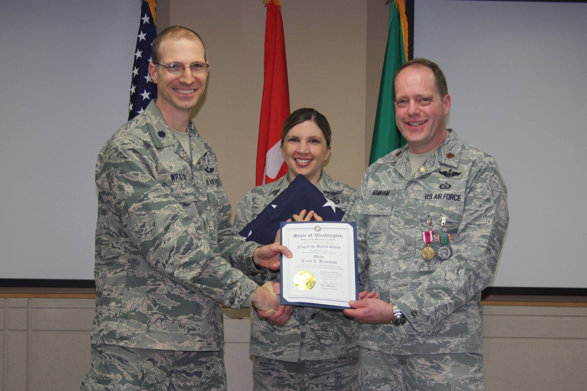 Lt. Col. Daniel Wrazien presents Major Trent Bramham with the U.S. flag flown over the State Capitol Building in Olympia in honor of his retirement.  He has held various positions during his career to include KC-135 aircraft pneudraulic system specialist, C-141 flight engineer, and an air battle manager at WADS. In his spare time, he earned his private pilot's license.(U.S. Air National Guard photo by Capt. Kimberly Burke/Released)