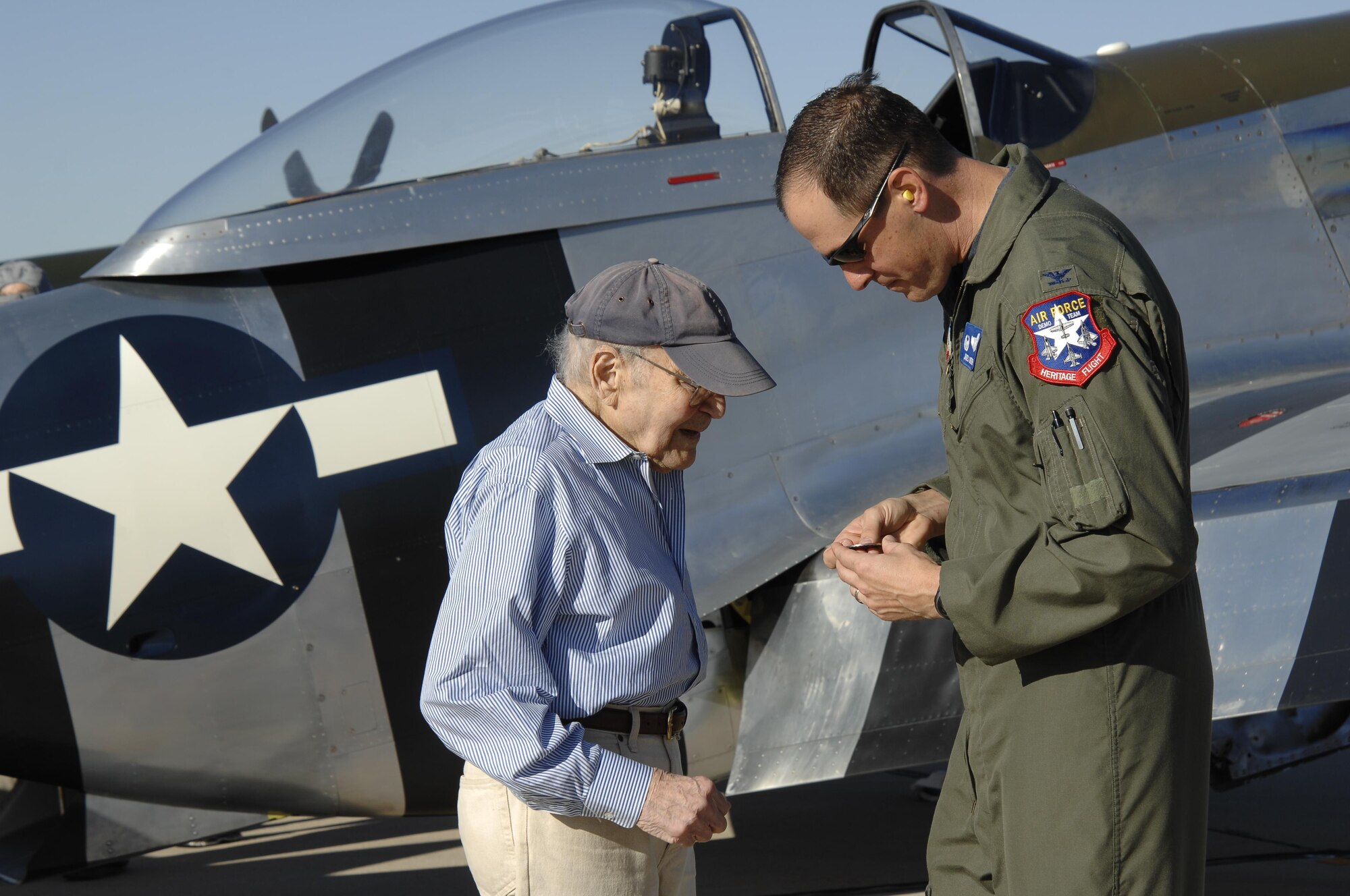 U.S. Air Force Col. James Meger presents U.S Air Force retired 1st Lt. William Lyons a coin for his service during the 2016 Heritage Flight Training and Certification Course at Davis-Monthan Air Force Base, Ariz., March 5, 2016. Lyons flew the P-51 Mustang during World War II. (U.S. Air Force photo by Tech. Sgt. Courtney Richardson/Released)