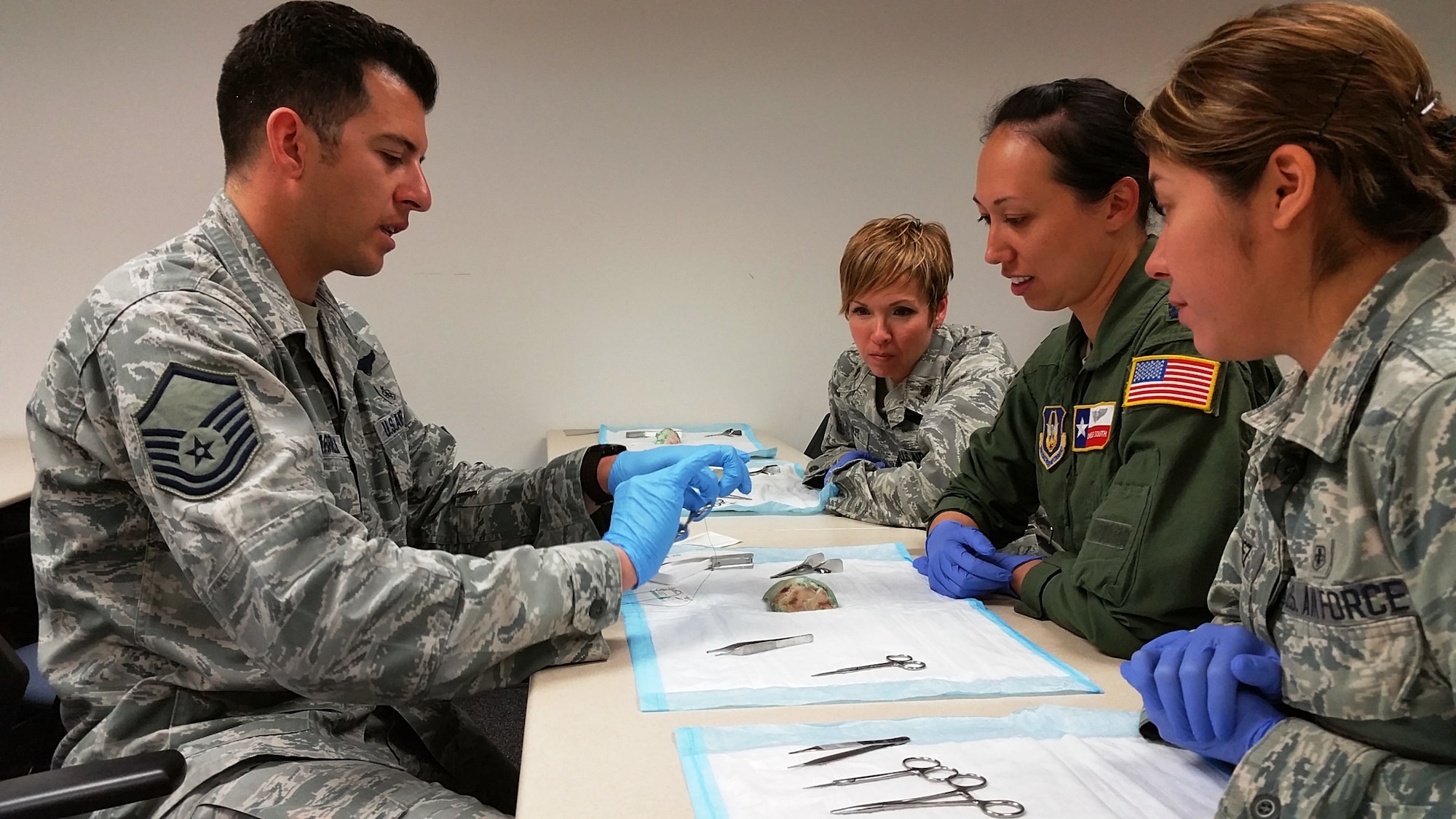 Master Sgt. Tito Carrillo (left), medical technician with the 433rd Aeromedical Evacuation Squadron, demonstrates suturing techniques to Maj. Emily Wolfe(top) and Capt. Charlie South(center), 433rd AES nurses, and Senior Airman Vania Perez(right), 433rd AES medical technician on March 4, 2016 at Joint Base San Antonio-Lackland, Texas.  Personnel with the 433rd AES and the 433rd Aeromedical Staging Squadron attended various classes to learn and practice their skills and test their abilities. (U.S. Air Force photo by Tech. Sgt. Carlos J. Trevino)