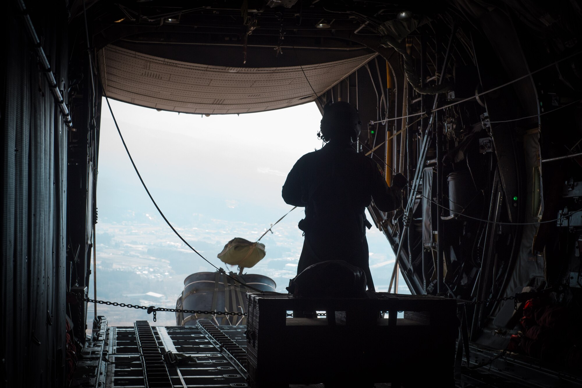 Master Sgt. Richard LaFrance, 36th Airlift Squadron loadmaster, watches a pallet drop from a C-130 Hercules while flying over Camp Fuji, Japan, March 4, 2016. The 36 AS uses pallets such as this one, called a high-velocity container delivery system, to simulate airdrop procedures for supplies.  (U.S. Air Force photo by Staff Sgt. Michael Smith/Released)   