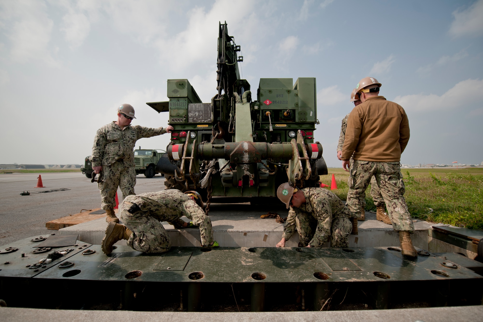 U.S. Navy Seabees assigned to Naval Mobile Construction Battalion 3 secure chains to a fairlead beam on the flight line Feb. 29, 2016, at Kadena Air Base, Japan. Seabees brought heavy equipment to the site in order to replace the aircraft arresting barrier system, which needs a complete overhaul every ten years. (U.S. Air Force photo by Senior Airman Peter Reft)