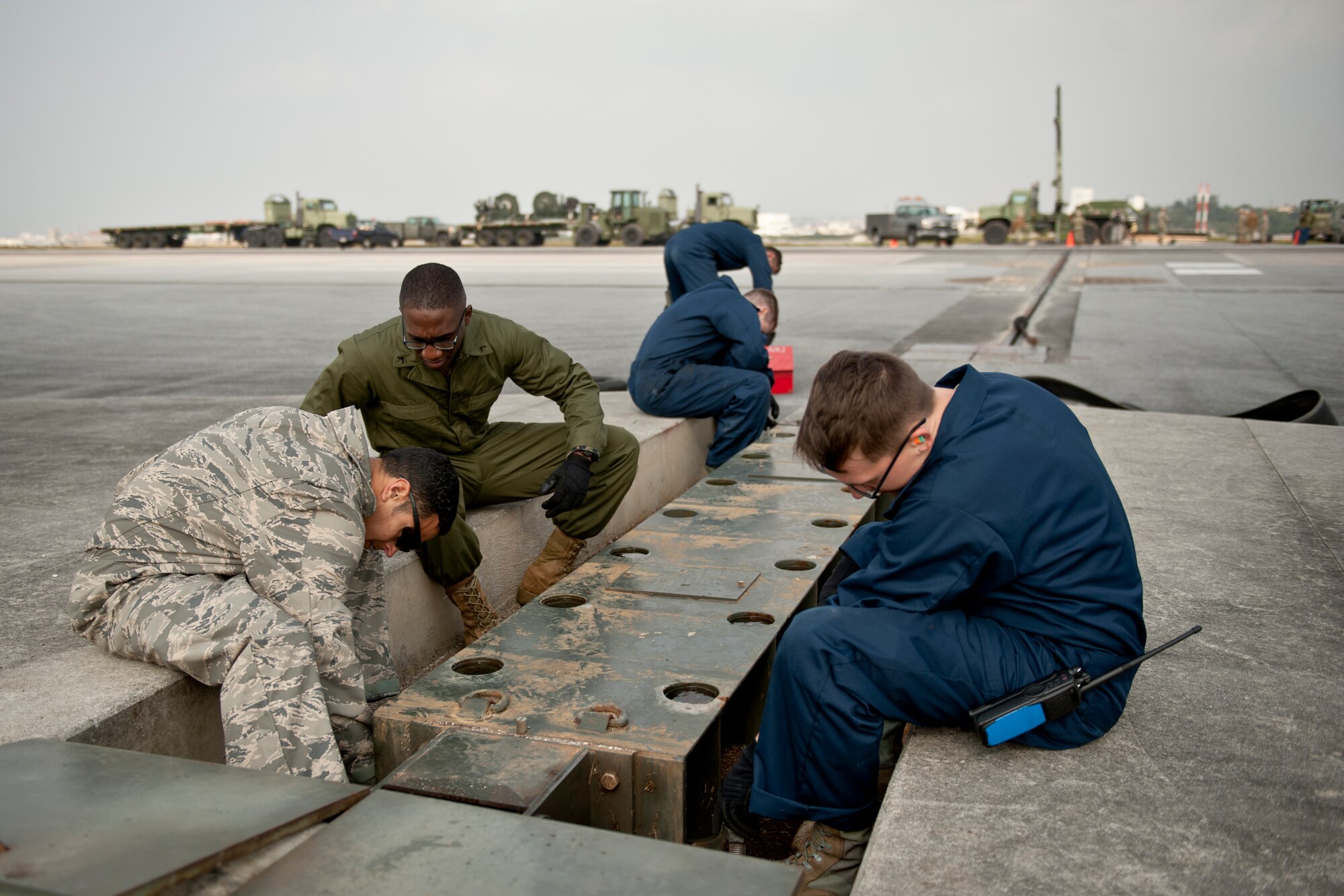 U.S. Air Force Staff Sgt. Emmanuel Flores, 18th Civil Engineer Squadron electrical power production craftsman, U.S. Marine Corps Private 1st Class Byron Beason, Marine Wing Support Squadron 172 expeditionary airfield service technician, and Airman 1st Class Austin Ohst, 18th CES electrical power production journeyman, unfasten bolts on a fairlead beam on the flight line Feb. 29, 2016, at Kadena Air Base, Japan. Engineer teams overhaul aircraft arresting barrier equipment with new systems as part of a scheduled maintenance every ten years. (U.S. Air Force photo by Senior Airman Peter Reft)