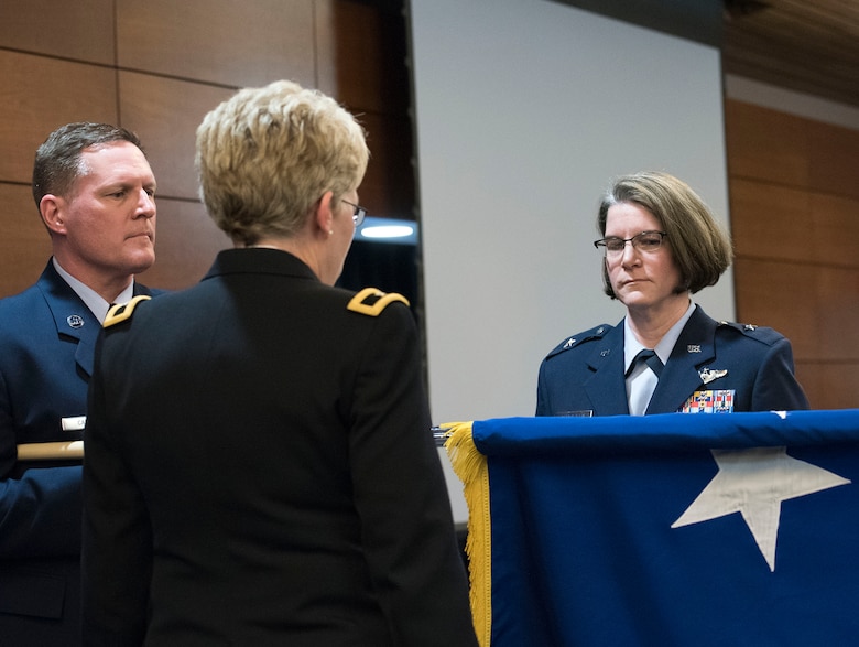 JOINT BASE ELMENDORF-RICHARDSON, Alaska -- Chief Master Sgt. Steven Calvin, the state command chief for the Alaska Air National Guard, unfurls the general's flag for new Brig. Gen. Karen Mansfield (right), commander of the Alaska Air National Guard, in a promotion ceremony at the Arctic Warrior Events Center here March 6, 2016. Mansfield became the third female general officer in the history of the Alaska Air National Guard. National Guard photo by Capt. John Callahan.