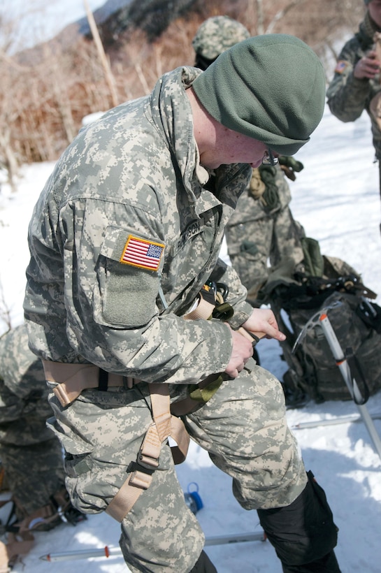 A soldier puts on his climbing gear at Smuggler's Notch in Jeffersonville, Vt., March 5, 2016. Vermont Army National Guard photo by Spc. Avery Cunningham