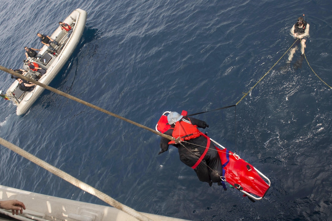 Navy Petty Officer 2nd Class Deon Farmer, right, steadies a rope while sailors aboard the USNS Spearhead raise a mock patient during a man overboard drill in the Atlantic Ocean, March 3, 2016. Farmer is a boatswain's mate, search-and-rescue swimmer assigned to the USNS Spearhead. Navy photo by Petty Officer 3rd Class Amy M. Ressler