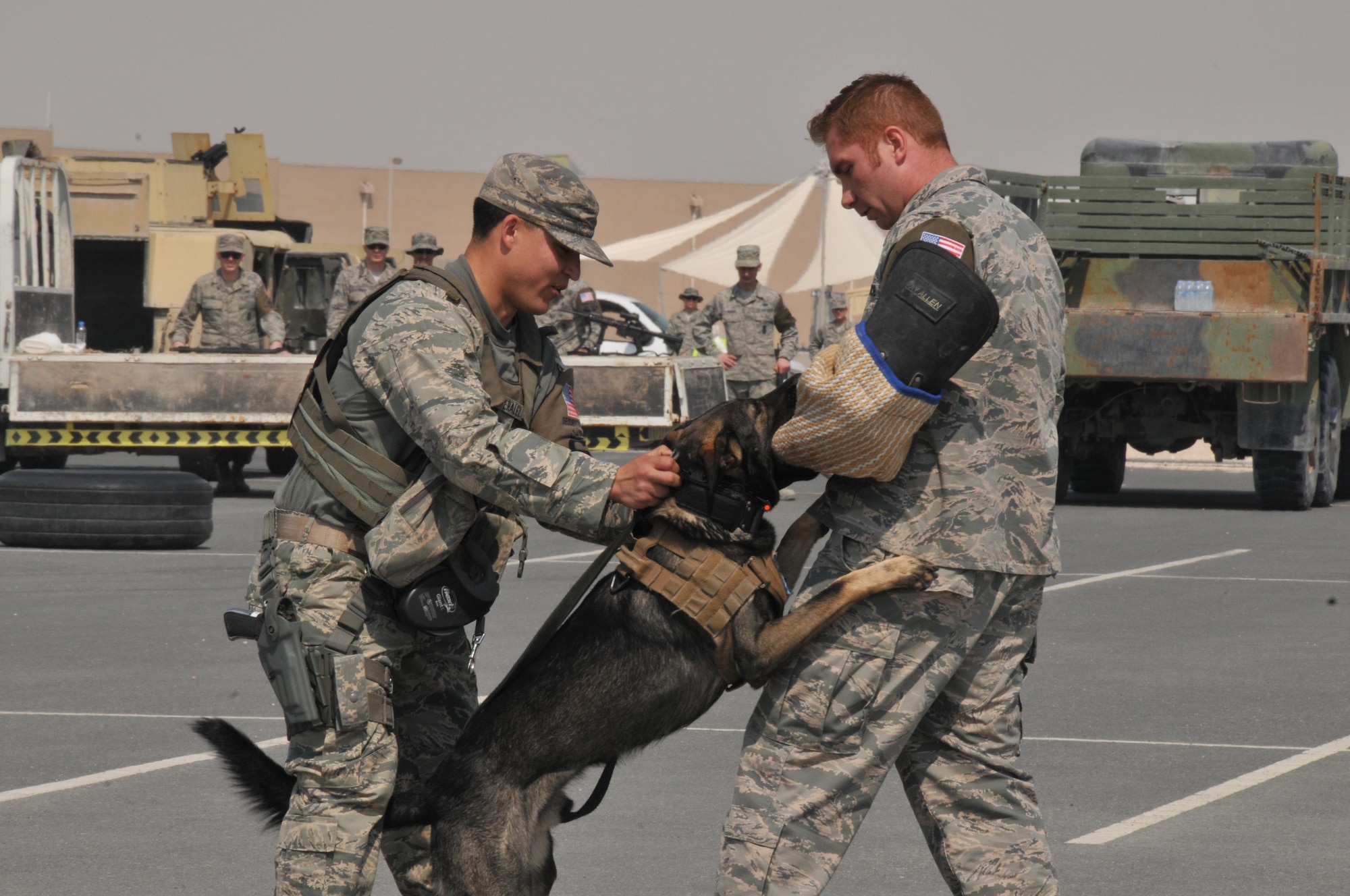 Staff Sgt. Michael Peralez, 379th Expeditionary Security Forces Squadron military working dog handler (left), Rogane, and Tech. Sgt. Shawn Rankins a decoy (right), performs a MWD demonstration for eighth grade students from the American School of Doha at Al Udeid Air Base, Qatar, Mar. 3.Students watched as the K-9 team performed differenttactics pertaining to their job. (U.S. Air Force photo by Tech. Sgt. Terrica Y. Jones)