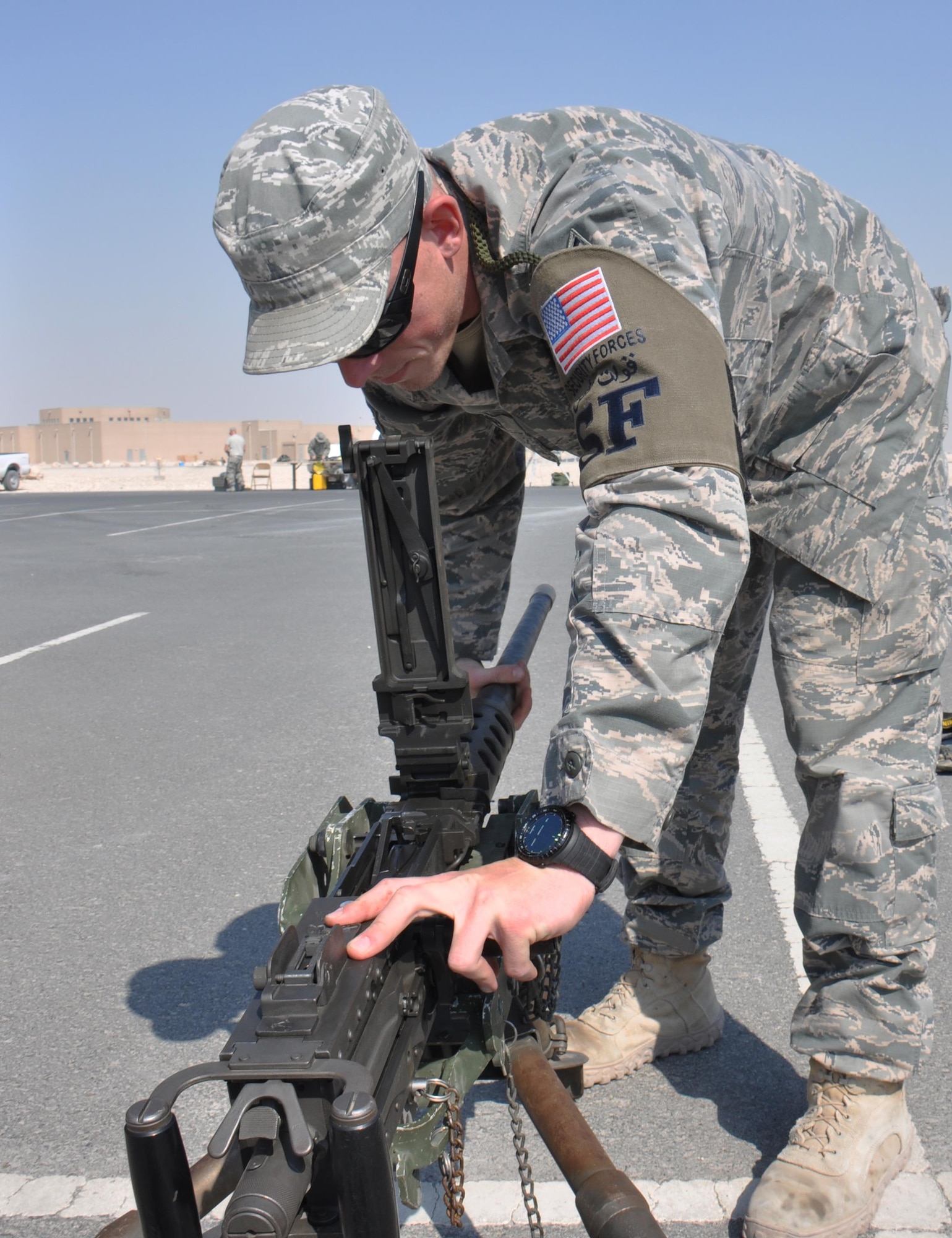 Staff Sgt. Jacob Seberger, 379th Expeditionary Security Forces Squadron, sets up a machine gun for a weapons display in the Blatchford Preston Complex gym parking lot at Al Udeid Air Base, Qatar March 3, before a visit from by approximately 200 American School of Doha students. The weapons display also featured an M-870 shotgun, M-4 rifle and a grenade launcher. During the visit, students watched a military working dog demonstration, toured a KC-135 Stratotanker and met with U.S. Airmen from a variety of specialties. (U.S. Air Force photo by Tech. Sgt. James Hodgman/Released)