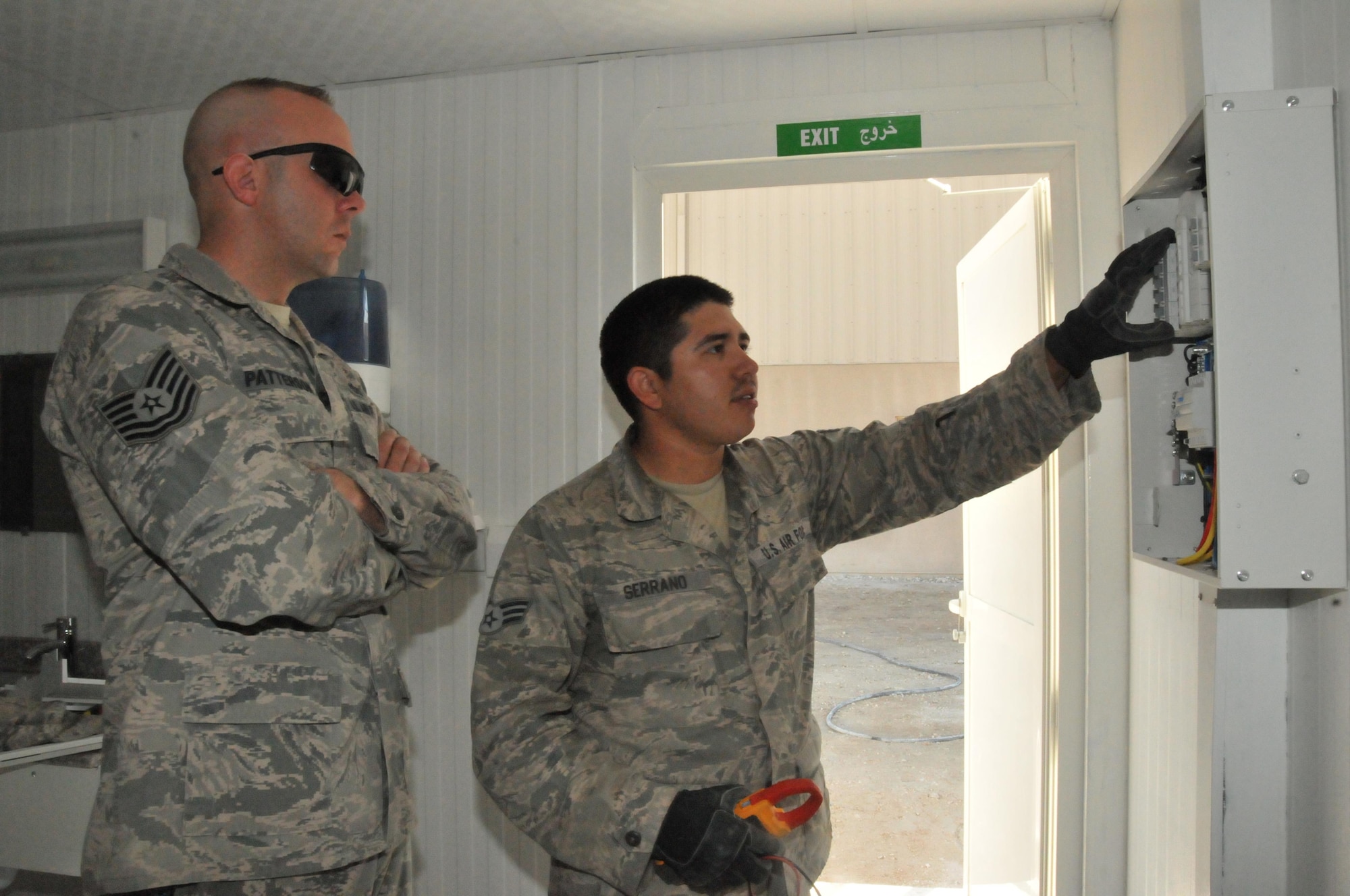 Senior Airman Cruz Serrano, 379th Expeditionary Civil Engineer Squadron electrician (right) discusses with Tech. Sgt. Charles Patterson (left), 379th ECES noncommissioned officer in charge of Cadillac Renovation Team, about what is causing the breaker to trip in one of the latrine units or Cadillacs Mar. 1 at Al Udeid Air Base, Qatar. (U.S. Air Force photo by Tech. Sgt. Terrica Y. Jones)