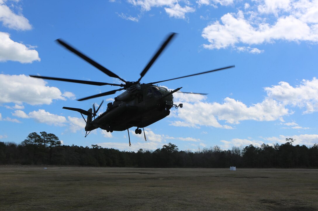 A CH-53E Super Stallion prepares to pick up its intended cargo during a helicopter support team exercise, aided by Marines with Landing Support Platoon, Combat Logistics Battalion 2 at Camp Lejeune, N.C., March 2, 2016. The training allows squadron pilots to practice loading and unloading cargo from a CH-53 Super Stallion without touching the ground, as well as allow the Marines with CLB-2 to sharpen their reaction times while helping load and unload cargo. The Marines working underneath the Super Stallion all have critical roles in ensuring mission accomplishment, working together to attach the equipment on the ground  to the helicopter while it hovers in the air about 10 feet above them. (Marine Corps photo by Cpl. Shannon Kroening)
