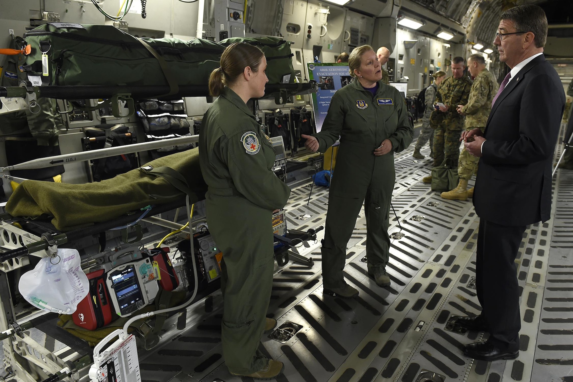 Maj. Beverly Davidson (center), 446th Aeromedical Evacuation Squadron flight nurse, and Tech. Sgt. Kassy Kvam (left), 446th AES flying medical technician, brief Defense Secretary Ash Carter about aeromedical evacuation procedures March 4, 2016 here. Carter spoke of the total force concept at JBLM, and this was just one of the demonstrations, which highlighted the concept. (U.S. Air Force photo by Tech. Sgt. Tim Chacon)