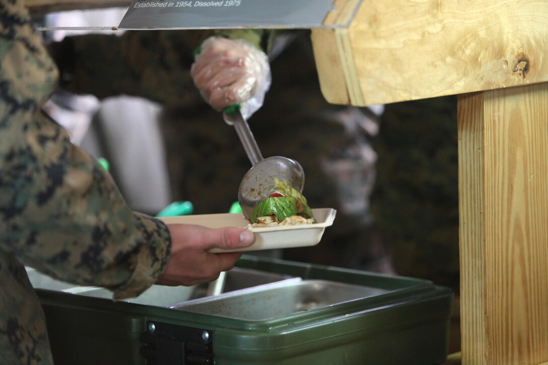 Food service specialists serve food to Marines at Marine Corps Air Station Cherry Point, N.C., Jan. 20, 2016. Marines with Marine Wing Support Squadron 274 cooked various dishes in a field-like environment to compete in the Maj. Gen. William Pendleton Thompson Hill Food Service Award competition. The Marines prepared dishes like shrimp and ham jambalaya, onion scallion beef and Vietnamese chicken noodle soup. In addition to being critiqued on the production of the food, the Marines were critiqued on sanitation and preparation. (U.S. Marine Corps photo by Cpl. Unique Roberts/ Released)