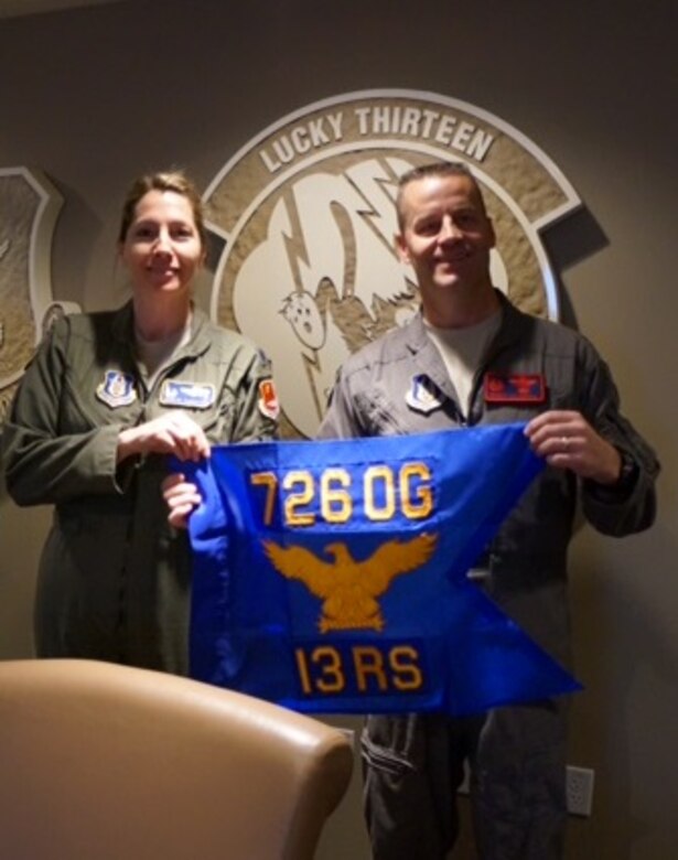 (Left to right) Lt. Col. Karyn, 13th Reconnaissance Squadron commander, and Col. Brent, 726th Operations Group commander, showcase the units' new guideon flag during an assimilation ceremony at Beale Air Force Base, Calif., on Feb. 10. (U.S. Air Force photo/Maj. Daniel)