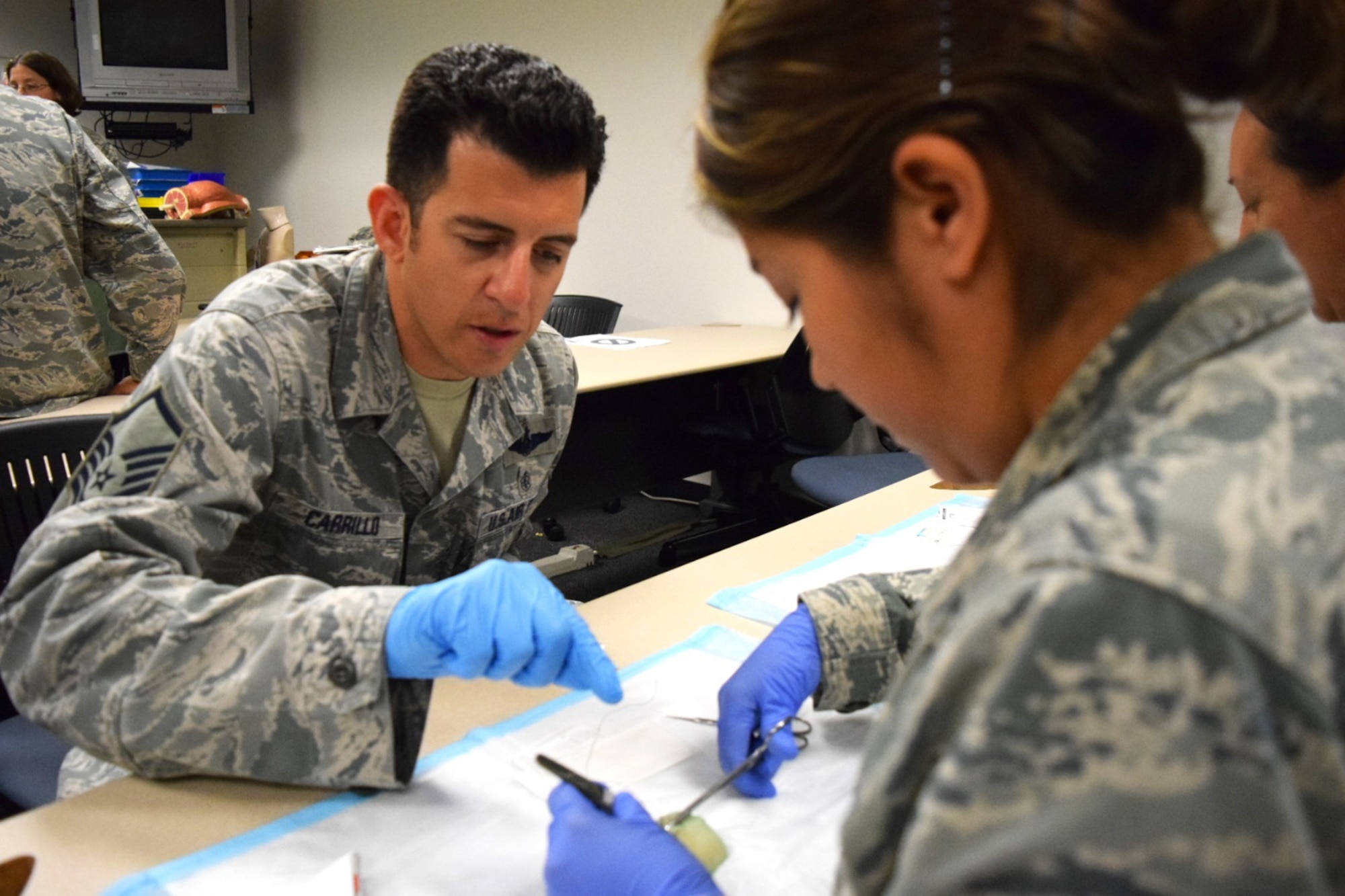 Master Sgt. Tito Carrillo (left), medical technician with the 433rd Aeromedical Evacuation Squadron, points out how to turn the forceps  to stitch skin on a pigs foot on March 4, 2016 at Joint Base San Antonio-Lackland, Texas to Senior Airman Vania Perez, also a 433rd AES aeromedical evacuation technician.  One of the many training sessions the medics and nurses participated in on the super UTA was learning to stitch pig skin due to its similarity to human skin.  (U.S. Air Force photo by Tech. Sgt. Carlos J. Trevino)

