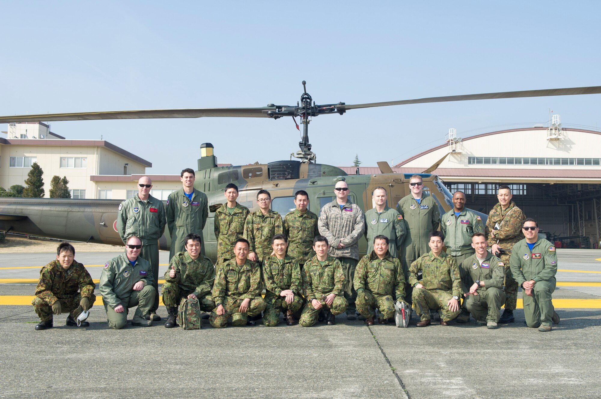 Crewmembers with the Japan Ground Self-Defense Force Eastern Army Helicopter, 1st Aviation and U.S. Air Force 459th Airlift Squadron pose for a photo by JGSDF UH-1J Iroquois at Yokota Air Base, Japan, March 4, 2016. The crewmembers exchanged search and rescue knowledge through hoist demonstration. (U.S. Air Force photo by Airman 1st Class Delano Scott/Released) 