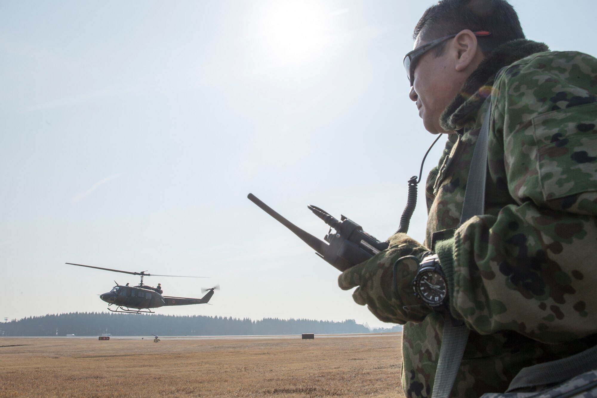 Japan Ground Self-Defense Force Lt. Col. Tatsuro Sakaguchi, Eastern Army Helicopter, 1st Aviation executive officer, communicates with JGSDF UH-1J’s crew members through a radio at Yokota Air Base, Japan, March 4, 2016. JGSDF members demonstrated their hoist capabilities to 459th Airlift Squadron members. (U.S. Air Force photo by Osakabe Yasuo/Released)