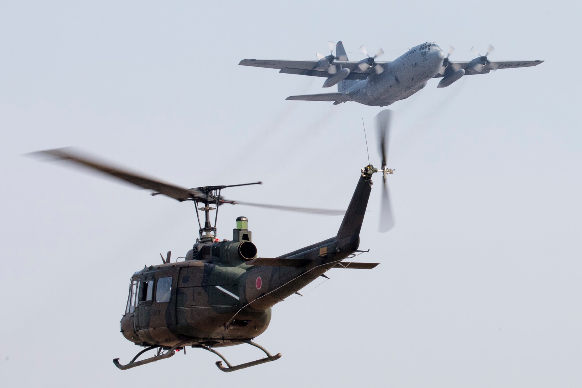 A Japan Ground Self-Defense Force UH-1J Iroquois and a U.S. Air Force C-130H Hercules fly over Yokota Air Base, Japan, March 8, 2016. The JGSDF UH-1J is assigned to the Eastern Helicopter, 1st Aviation and the USAF C-130H is assigned to the 36th Airlift Squadron. (U.S, Air Force photo by Osakabe Yasuo/Released) 