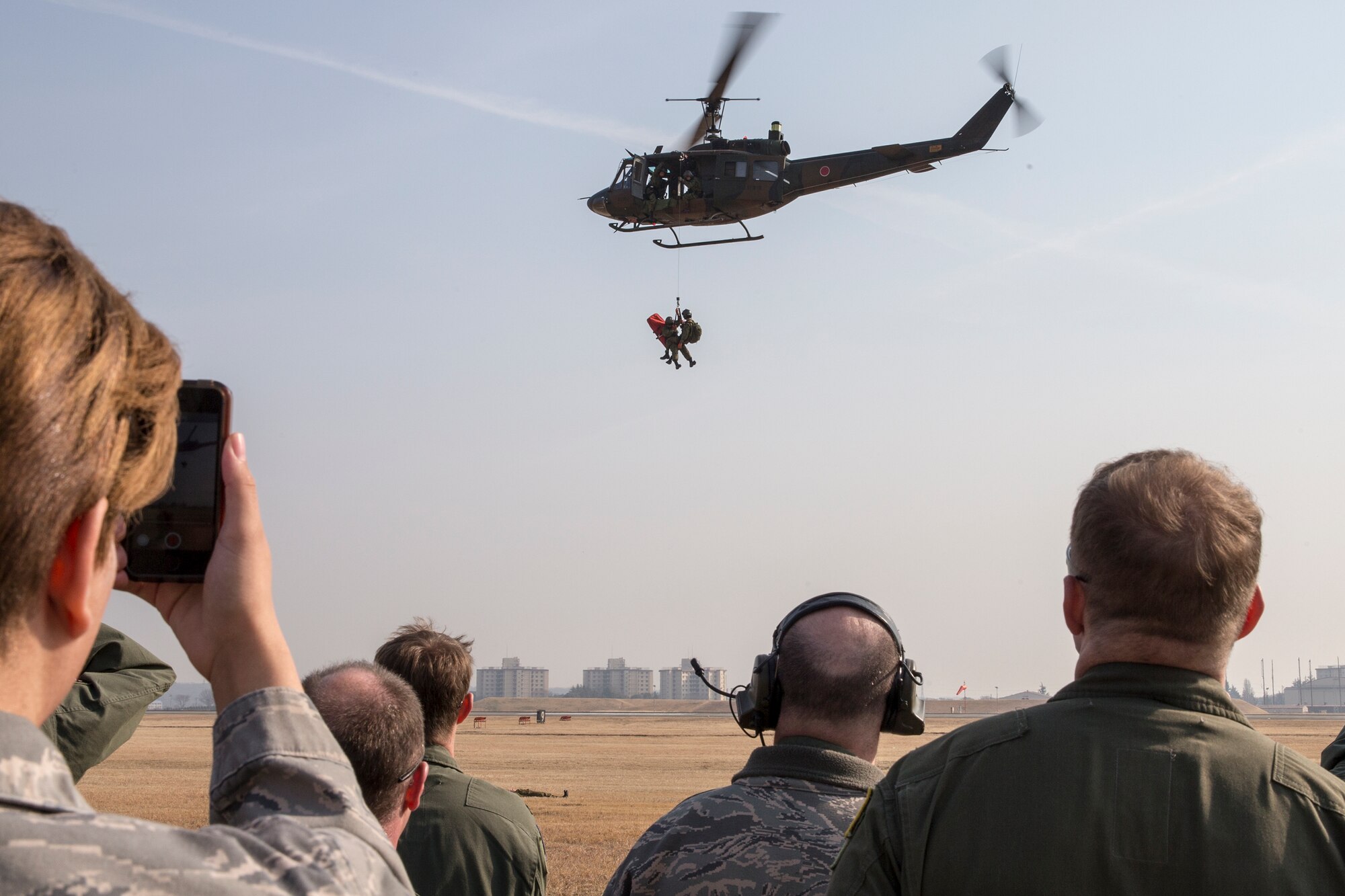 Airmen from the 459th Airlift Squadron watch a hoist demonstration performed by Japan Ground Self-Defense Force from the Eastern Army Helicopter, 1st Aviation, at Yokota Air Base, Japan, March 4, 2016.  JGSDF members with the 1st Aviation Unit supported the Kinugawa flood last year and rescued 104 people and four dogs in one hour. (U.S. Air Force photo by Osakabe Yasuo/Released) 
