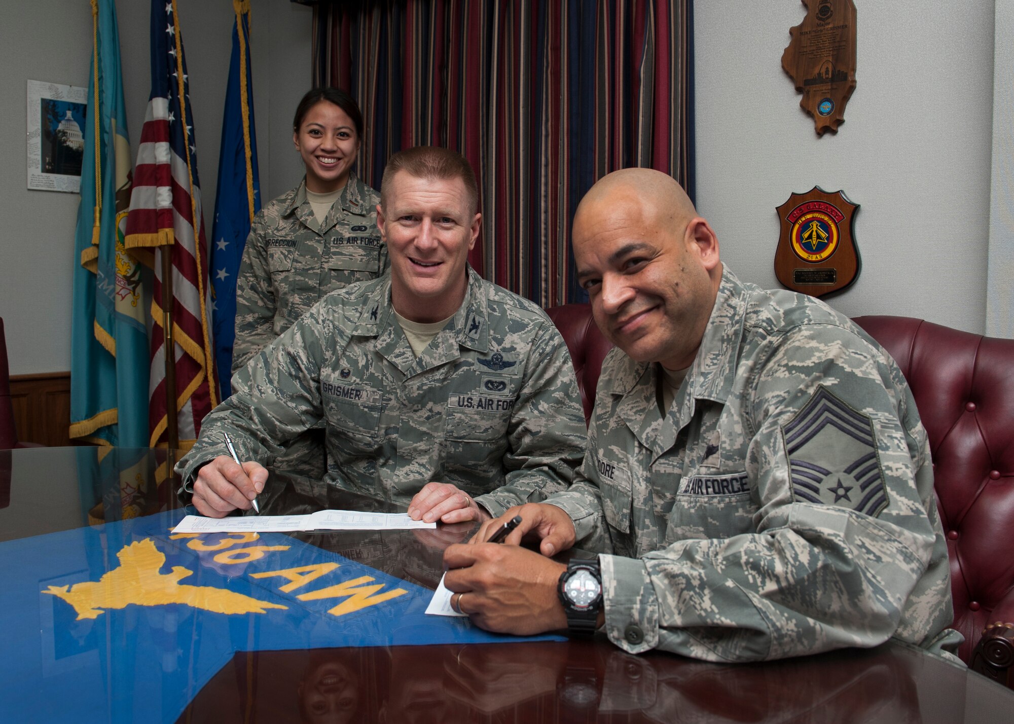 Col. Michael Grismer, 436th Airlift Wing commander, and Chief Master Sgt. Geraldo Moore, 436th AW interim command chief, fill out their Air Force Assistance Fund pledges Feb. 29, 2016, at Dover AFB, Del. Second Lt. Dawn Marie Resurreccion, 436th Force Support Squadron fitness center director, rear, is the primary installation project officer for the AFAF. (U.S. Air Force photo/Senior Airman Zachary Cacicia)