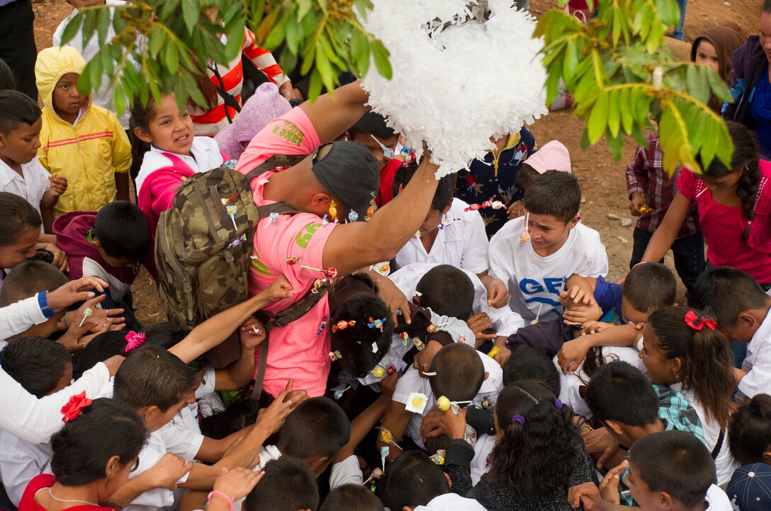 A member of Joint Task Force-Bravo helps open a piñata during Chapel Hike 66 at Tierra Colorada, March 5, 2016. During the regularly occurring hikes, service members and civilians from Soto Cano Air Base hike to villages local leaders identify as most in need of the goods the volunteers bring with them. (U.S. Air Force photo by Capt. Christopher Mesnard)