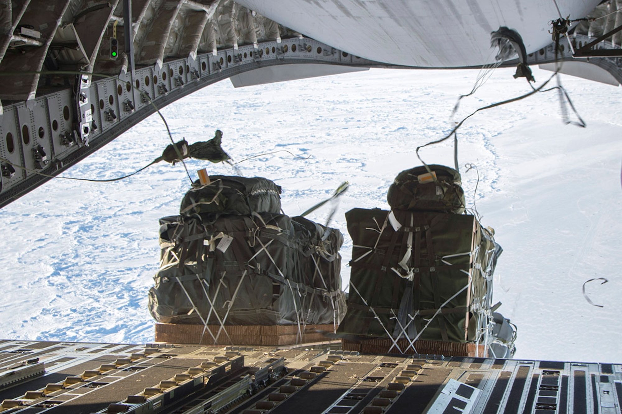 More than 12,000 pounds of cargo fall out of the back of a C-17 Globemaster III over the Arctic Ocean in support of the U.S. Navy Submarine Forces' Ice Exercise 2016.  The drop was made from 550 feet above ground level. (U.S. Air Force photo by Staff Sgt. Sheila deVera)


