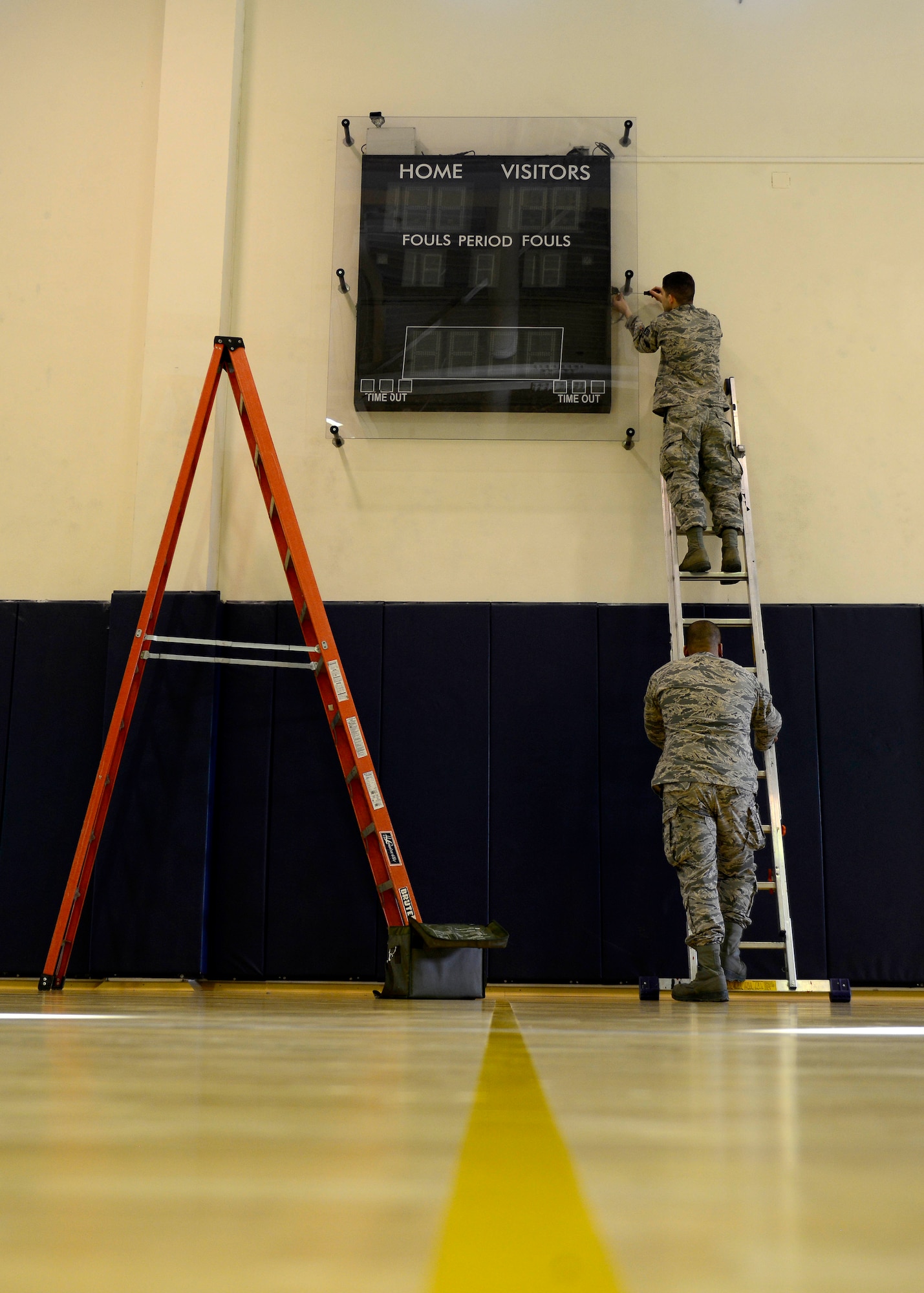 (From top) Staff Sgt. Phillip Gardner and Senior Airman Edgar Diaz, 31st Maintenance Group Air Force Repair Enhancement Program technicians, repair a score board, Feb. 25, 2016, at Aviano Air Base, Italy. Depeding on the time, AFREP members will evaulate and repair items on location. (U.S. Air Force photo by Senior Airman Areca T. Bell/Released)