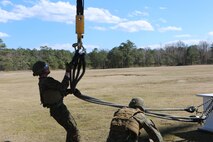 Marines with Landing Support platoon, Combat Logistics Battalion 2 connect the line to a CH-53E Super Stallion during a helicopter support team exercise aboard Camp Lejeune, N.C., March 2, 2016. The Marines working underneath the Super Stallion all have critical roles in ensuring mission accomplishment, working together to attach the equipment on the ground  to the helicopter while it hovers in the air about 10 feet above them. The training allows squadron pilots to practice loading and unloading cargo from a CH-53 Super Stallion without touching the ground, as well as allow the Marines with CLB-2 to sharpen their reaction times while helping load and unload the cargo. (Marine Corps photo by Cpl. Shannon Kroening)