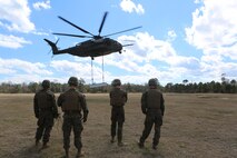 Marines with CLB-2 wait for the command to rush the cargo after it has been dropped by a CH-53E Super Stallion during a helicopter support team exercise aboard Camp Lejeune, N.C., March 2, 2016. The Marines working underneath the Super Stallion have critical roles in ensuring mission accomplishment, working together to attach the equipment on the ground  to the helicopter while it hovers in the air about 10 feet above them. The training allows squadron pilots to practice loading and unloading cargo from a CH-53 Super Stallion without touching the ground, as well as allow the Marines with CLB-2 to sharpen their reaction times while helping load and unload the cargo. (Marine Corps photo by Cpl. Shannon Kroening)