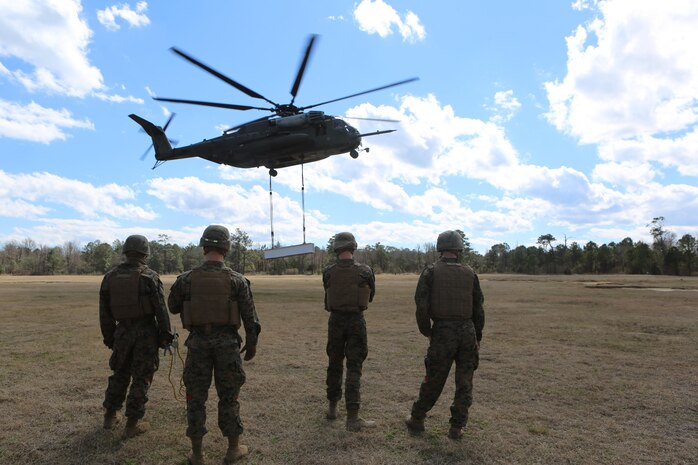 Marines with CLB-2 wait for the command to rush the cargo after it has been dropped by a CH-53E Super Stallion during a helicopter support team exercise aboard Camp Lejeune, N.C., March 2, 2016. The Marines working underneath the Super Stallion have critical roles in ensuring mission accomplishment, working together to attach the equipment on the ground  to the helicopter while it hovers in the air about 10 feet above them. The training allows squadron pilots to practice loading and unloading cargo from a CH-53 Super Stallion without touching the ground, as well as allow the Marines with CLB-2 to sharpen their reaction times while helping load and unload the cargo. (Marine Corps photo by Cpl. Shannon Kroening)