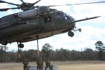 Marines with CLB-2 prepare to attach cargo to a CH-53E Super Stallion during a helicopter support team exercise aboard Camp Lejeune, N.C., March 2, 2016. The Marines working underneath the Super Stallion have critical roles in ensuring mission accomplishment, working together to attach the equipment on the ground  to the helicopter while it hovers in the air about 10 feet above them.  The training allows squadron pilots to practice loading and unloading cargo from a CH-53 Super Stallion without touching the ground, as well as allow the Marines with CLB-2 to sharpen their reaction times while helping load and unload the given cargo. (Marine Corps photo by Cpl. Shannon Kroening