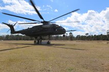 Marines with Combat Logistics Battalion 2 move quickly to attach cargo to a CH-53E Super Stallion during a helicopter support team exercise aboard Camp Lejeune, N.C., March 2, 2016. The Marines working underneath the Super Stallion have critical roles in ensuring mission accomplishment, they work together to attach the equipment on the ground  to the helicopter while it hovers in the air about 10 feet above them. In real world events, helicopter support team missions are critical to mission accomplishment because they provide the ability to quickly and efficiently provide support to Marines on the ground, loading and unloading important equipment such as small vehicles, supplies, and food rations in a moment’s notice.   (Marine Corps photo by Cpl. Shannon Kroening)