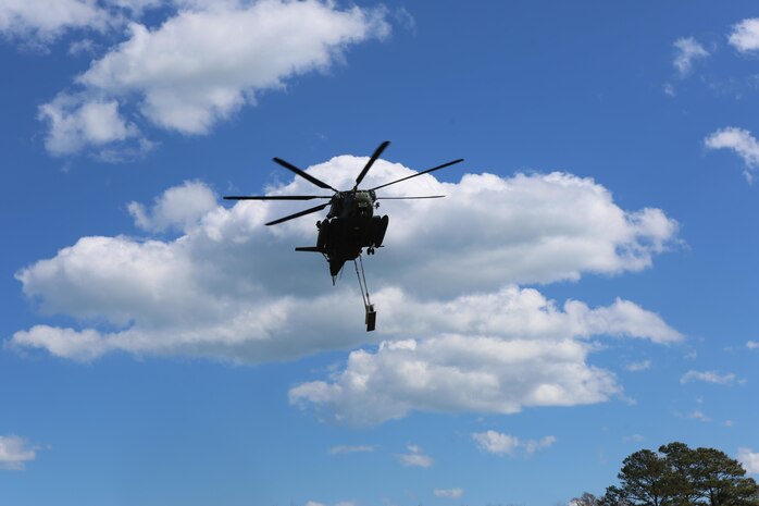 A CH-53E Super Stallion lifts cargo during a helicopter support training exercise aided by Marines with Landing Support platoon, Combat Logistics Battalion 2 aboard Camp Lejeune, N.C., March 2, 2016. The Marines underneath the Super Stallion all have critical roles in ensuring mission accomplishment, working together to attach the equipment on the ground  to the helicopter while it hovers in the air about 10 feet above them.  In real world events, helicopter support team missions are critical to mission accomplishment because they provide the ability to quickly and efficiently provide support to Marines on the ground, loading and unloading important equipment such as small vehicles, supplies, and food rations in a moment’s notice. (Marine Corps photo by Cpl. Shannon Kroening)