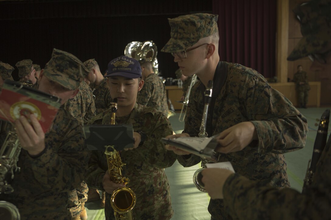 A Japan Ground Self Defense Force Western Army Band member helps Sgt. Michael A. Parker and Lance Cpl. Ivan E. Arden with queues during a rehearsal for the Western Army Band’s Music Festival Mar. 3 in an auditorium on Camp Kengun. The Marines will be marching out with the Western Army in sync from separate sides of a stage and meet in a joint formation. The music festival marks the 60th anniversary of the Western Army band. (U.S. Marine Corps photo by Cpl. Tyler Ngiraswei/ Released)