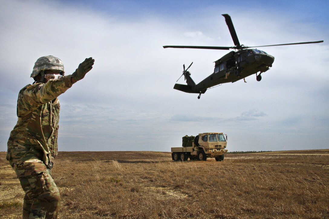 Army Sgt. Corey Collins directs a UH-60 Black Hawk helicopter during slingload training at Coyle drop zone on Joint Base McGuire-Dix-Lakehurst, N.J., Feb. 29, 2016. Collins is assigned to the Army Reserve’s 404th Civil Affairs Battalion Airborne. New Jersey Air National Guard photo by Tech. Sgt. Matt Hecht