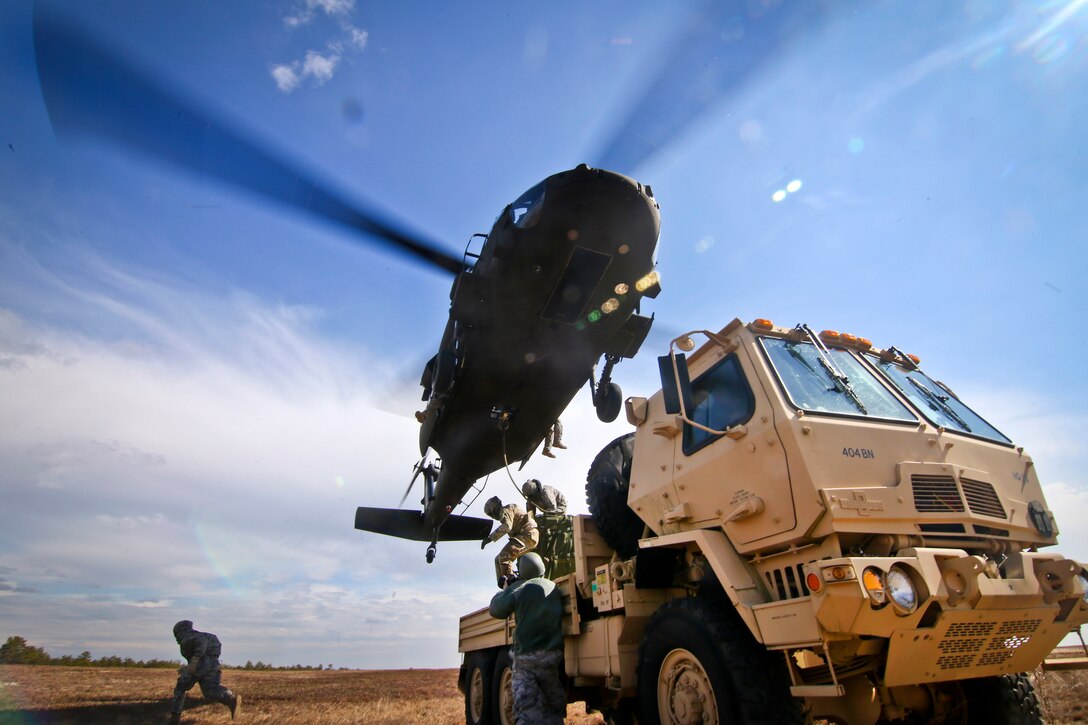 Soldiers run from their vehicle after successfully attaching cargo onto a UH-60 Black Hawk helicopter during slingload training at Coyle drop zone on Joint Base McGuire-Dix-Lakehurst, N.J., Feb. 29, 2016. New Jersey Air National Guard photo by Tech. Sgt. Matt Hecht