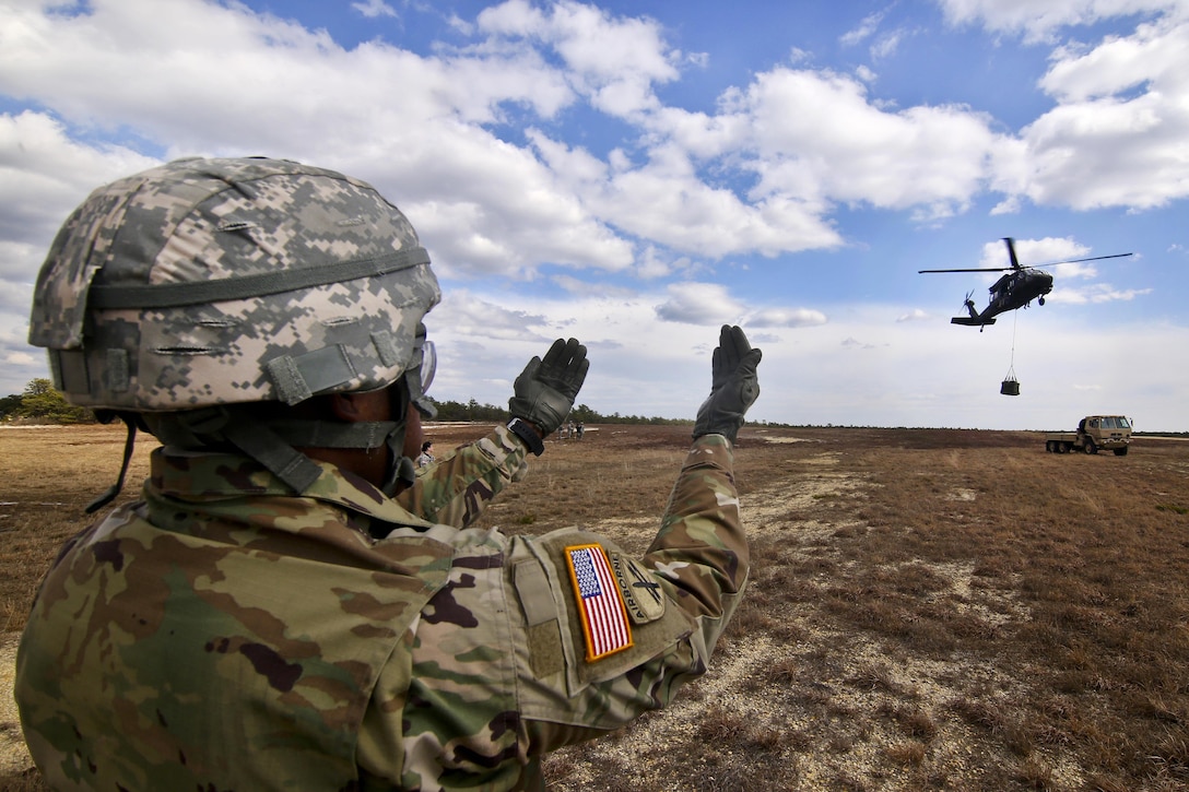 Army Sgt. Corey Collins signals a UH-60 Black Hawk helicopter crew during slingload training at Coyle drop zone on Joint Base McGuire-Dix-Lakehurst, N.J., Feb. 29, 2016. Collins is assigned to the Army Reserve’s 404th Civil Affairs Battalion Airborne. New Jersey Air National Guard photo by Tech. Sgt. Matt Hecht
