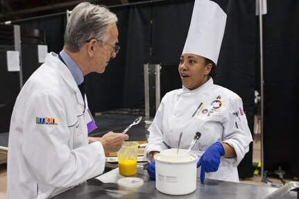 Staff Sgt. Aqueelah James, a U.S. Army Reserve Culinary Team member with the 3rd Medical Command (Deployment Support), Fort Gillem, Ga., talks with Chef judge Gunther Heiland about her Island Dream Dessert during the Practical and Contemporary Hot Food Cooking/Patisserie category at the 41st Annual Military Culinary Arts Competitive Training Event, March 7, 2016, at Fort Lee, Va. James, who earned a silver medal in the category, used the influences of her family heritage from the islands of Saint Kitts and Nevis and the Dominican Republic, as inspiration for the dessert. (U.S. Army photo by Timothy L. Hale/Released)