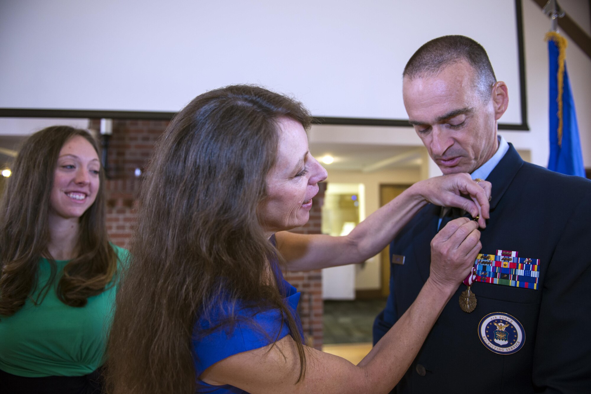 Robin Dyson, wife of Chief Master Sgt. Edward Dyson, 336th Recruiting Squadron superintendent, places a retirement pin on Dyson’s lapel as their daughter, Jessica Watkins, watches during his retirement ceremony, March 4, 2016, at Moody Air Force Base, Ga. Robin and Jessica received certificates of appreciation for their commitment and numerous contributions to the Air Force and the Nation. (U.S. Air Force photo by Airman 1st Class Greg Nash/Released) 