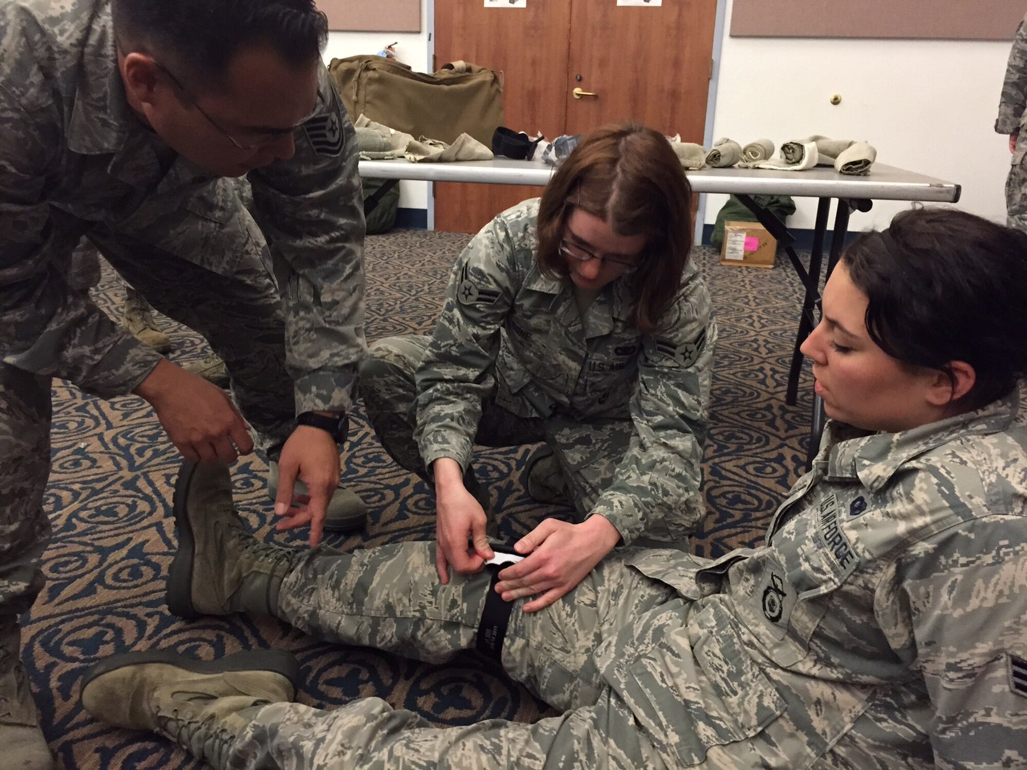 Tech. Sgt. Stacy Baird, 940th Force Support Squadron personnelist, instructs two 940th Security Forces Senior Airmen, Amanda Cone (then Airman 1st Class) and Jenny Keck, on how to use a combat application tourniquet during annual first aid training, at Beale Air Force Base, California, March 6, 2016. If using direct pressure and pressure points haven’t worked to stop blood loss, a CAT is used as a last resort to control severe bleeding. Around 120 reservists participated in the training – learning about CPR, bleeding control, how to treat shock, wound care, etc. (U.S. Air Force photo by Tech. Sgt. Heather Skinkle)