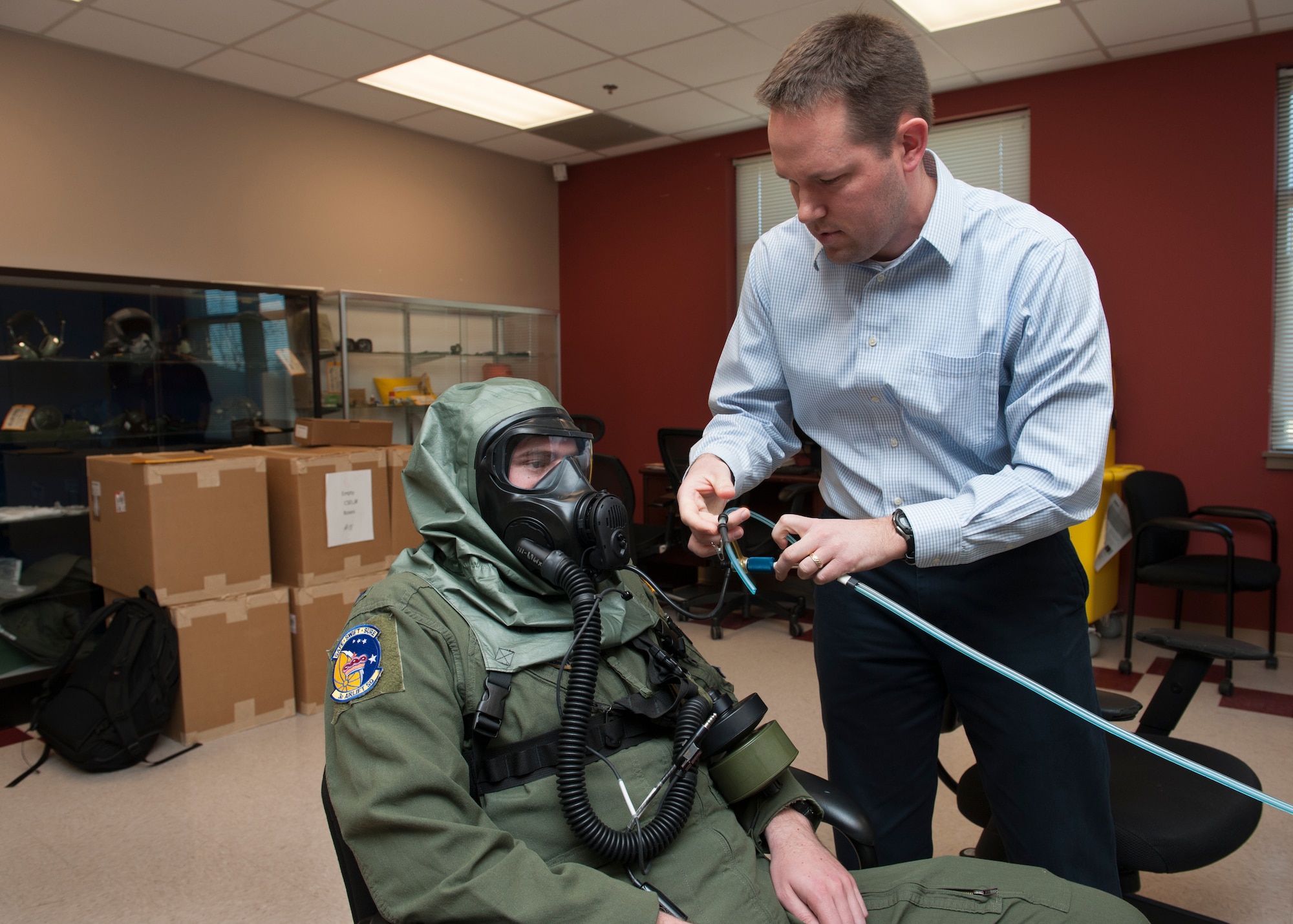 Zachary Chadwick, Joint Project Manager protection test engineer, attaches the Joint Service Mask Leakage Tester to the XM69 Aircrew Chemical, Biological, Radiological and Nuclear Defense (CBRN) system worn by 1st Lt. Rich Gangloff, 3d Airlift Squadron pilot, March 2, 2016, inside the Aircrew Flight Equipment facility on Dover Air Force Base, Del. Gangloff was one of ten Airmen from the 3d AS to volunteer to wear the XM69. (U.S. Air Force photo/Senior Airman Zachary Cacicia)