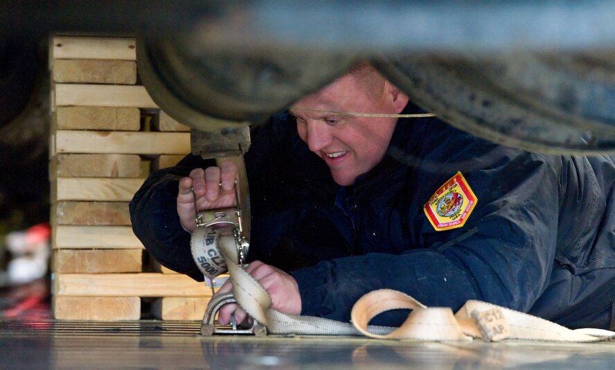 Eddie Thurston, Fairfax County Fire and Rescue Department, Va.: Virginia Task Force 1 medical specialist, hooks a tie-down strap to a C-5M Super Galaxy cargo compartment floor D-ring March 3, 2016, on Dover Air Force Base, Del. Thurston was one of 22 Urban Search and Rescue Team personnel along with approximately 30 loadmasters from units within the 436th and 512th Airlift Wings that practiced loading and securing a total of eight USRT vehicles. (U.S. Air Force photo/Roland Balik)