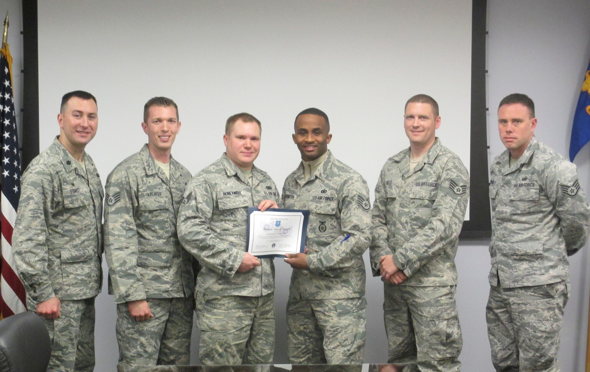 Staff Sgt. De Andre Harrington, 436th Security Force Squadron and Team 5/6 president, presents Senior Airman Joseph Honeywell, 436th Contracting Squadron contracting specialist, with the Team 5/6 Airman “Sharp” Award March 3, 3016, at Dover Air Force Base, Del. The Airman “Sharp” Award recognizes Team Dover Airmen who reflect extraordinary performance while performing mission requirements. (Courtesy photo)