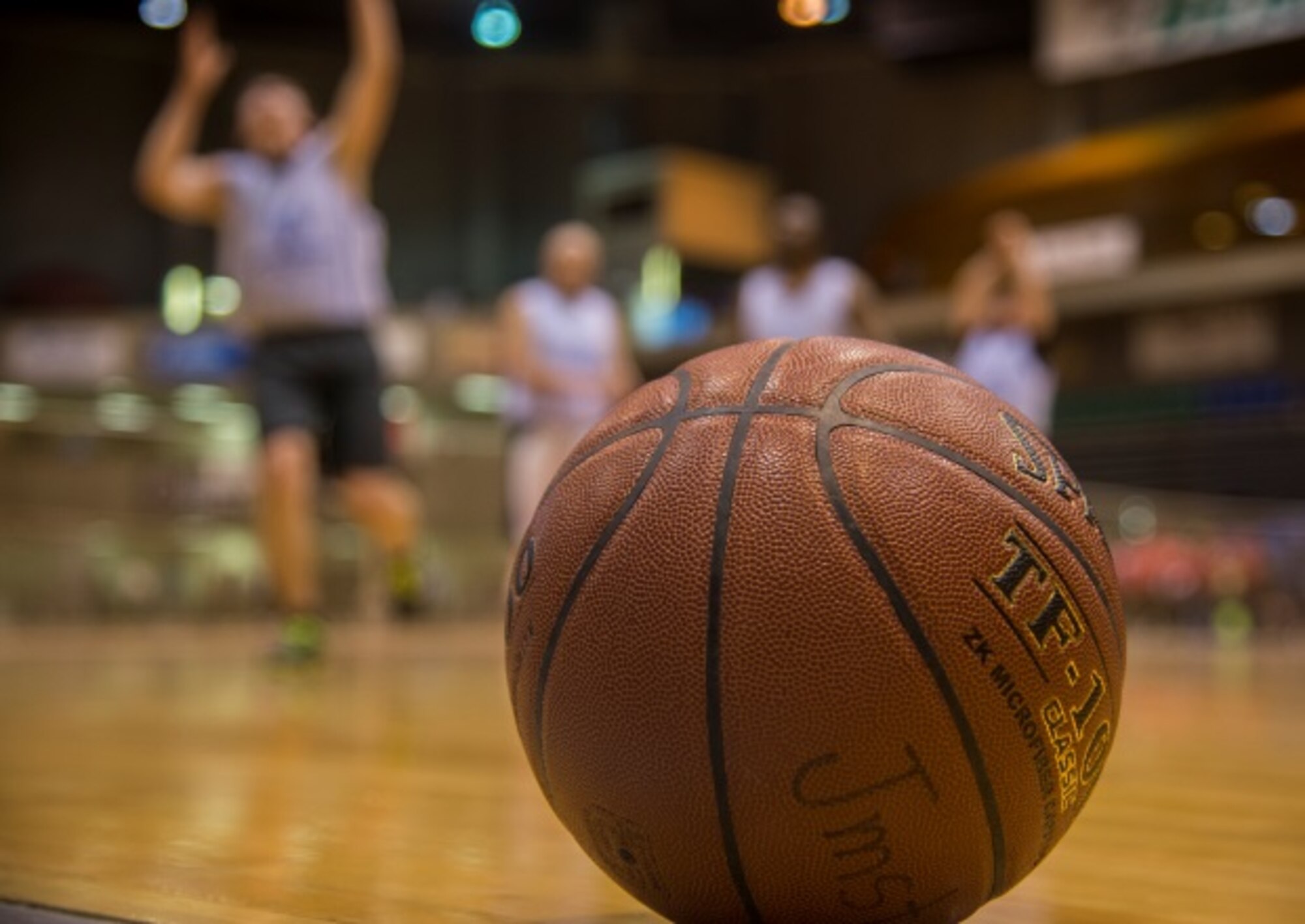 A basketball sits on the gym floor while participants warm up for the North Dakota Special Olympics in Minot, N.D., March 4, 2016. Minot Air Force Base members volunteered at the event as referees and other volunteer positions. (U.S. Air Force photo/Airman 1st Class Christian Sullivan)