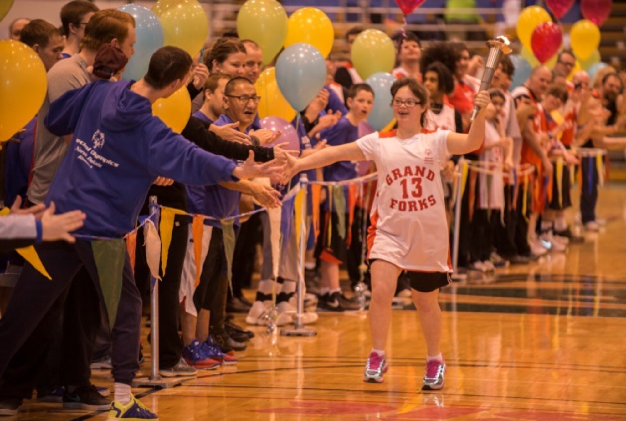 North Dakota Special Olympics female athlete of the year, Bailey Bjorge, carries the torch during the pre-game ceremonies at the North Dakota Special Olympics in Minot, N.D., March 4, 2016. Minot Air Force Base members volunteered at the event as referees and other volunteer positions. (U.S. Air Force photo/Airman 1st Class Christian Sullivan)