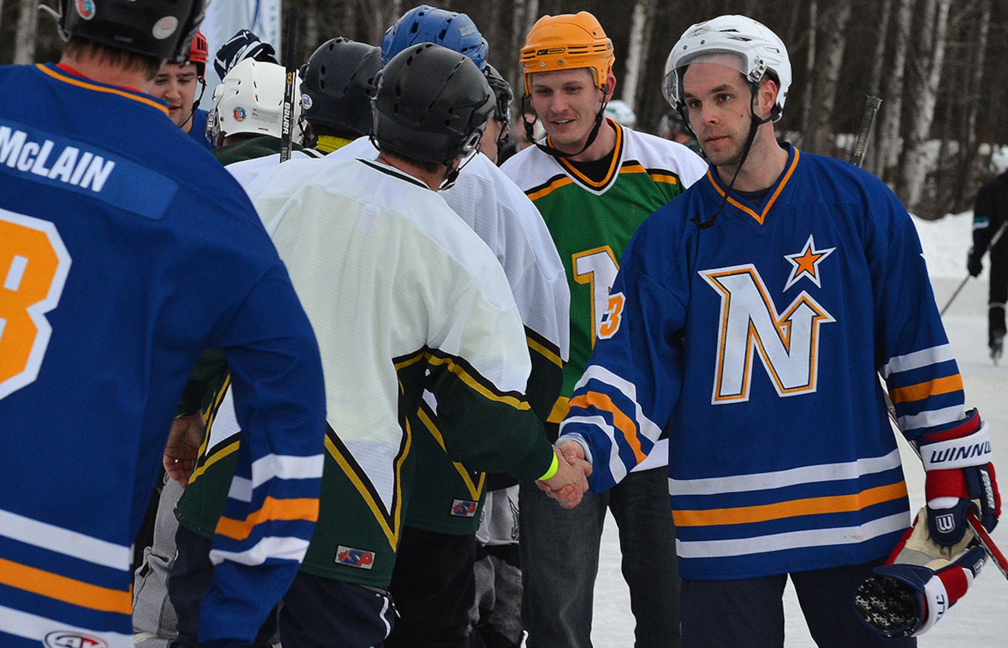 Senior Airman James Richardson, a photojournalist with the 673d Air Base Wing Public Affairs Office, and Air Force Staff Sgt. Tony Zubriski, an air traffic controller with the 3rd Operational Support Squadron shake hands with the opposing team after their first victory at The Last Frontier Pond Hockey Classic hosted in Anchorage, Alaska March 5. Their team finished the tournament with a match score of two losses, one win, and a tie in the open division. (U.S. Air Force photo by Airman 1st Class Kyle Johnson)