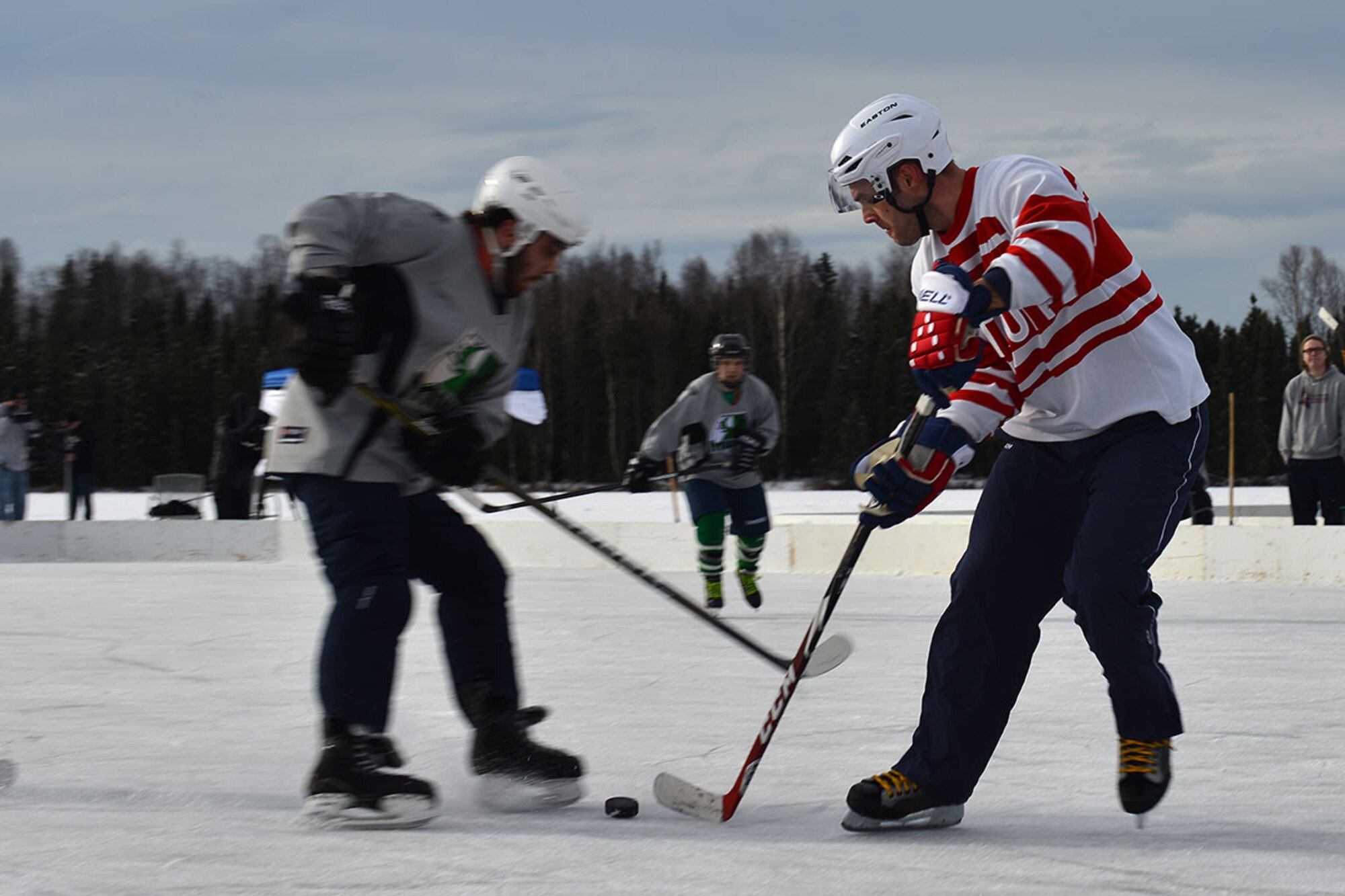 Senior Airman James Richardson, a photojournalist with the 673d Air Base Wing Public Affairs Office, dips the puck past an opponent at The Last Frontier Pond Hockey Classic hosted in Anchorage, Alaska March 5. The tournament was held as part of the Fur Rendezvous festivities, and featured eight separate divisions, each with multiple groups of teams competing to be the best in their respective division. (U.S. Air Force photo by Airman 1st Class Kyle Johnson)