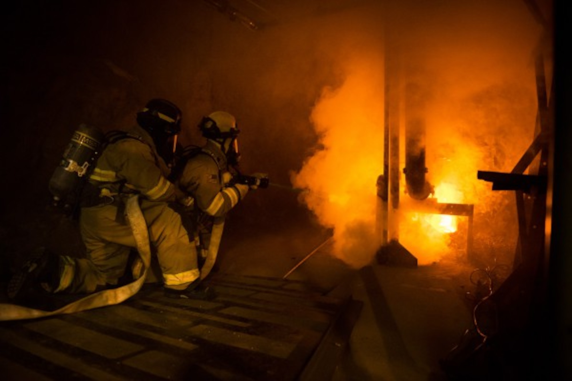 CHEYENNE MOUNTAIN AIR FORCE STATION, Colo. - Kenny Geates and Eric Skinner, both firefighters with Cheyenne Mountain’s Fire and Emergency Services Flight, put out a simulated fire in an area underneath the facility during an exercise. With no room to drive throughout the facility to reach the fires, firefighters have to run to them. (Photo by Staff Sgt. Andrew Lee )
