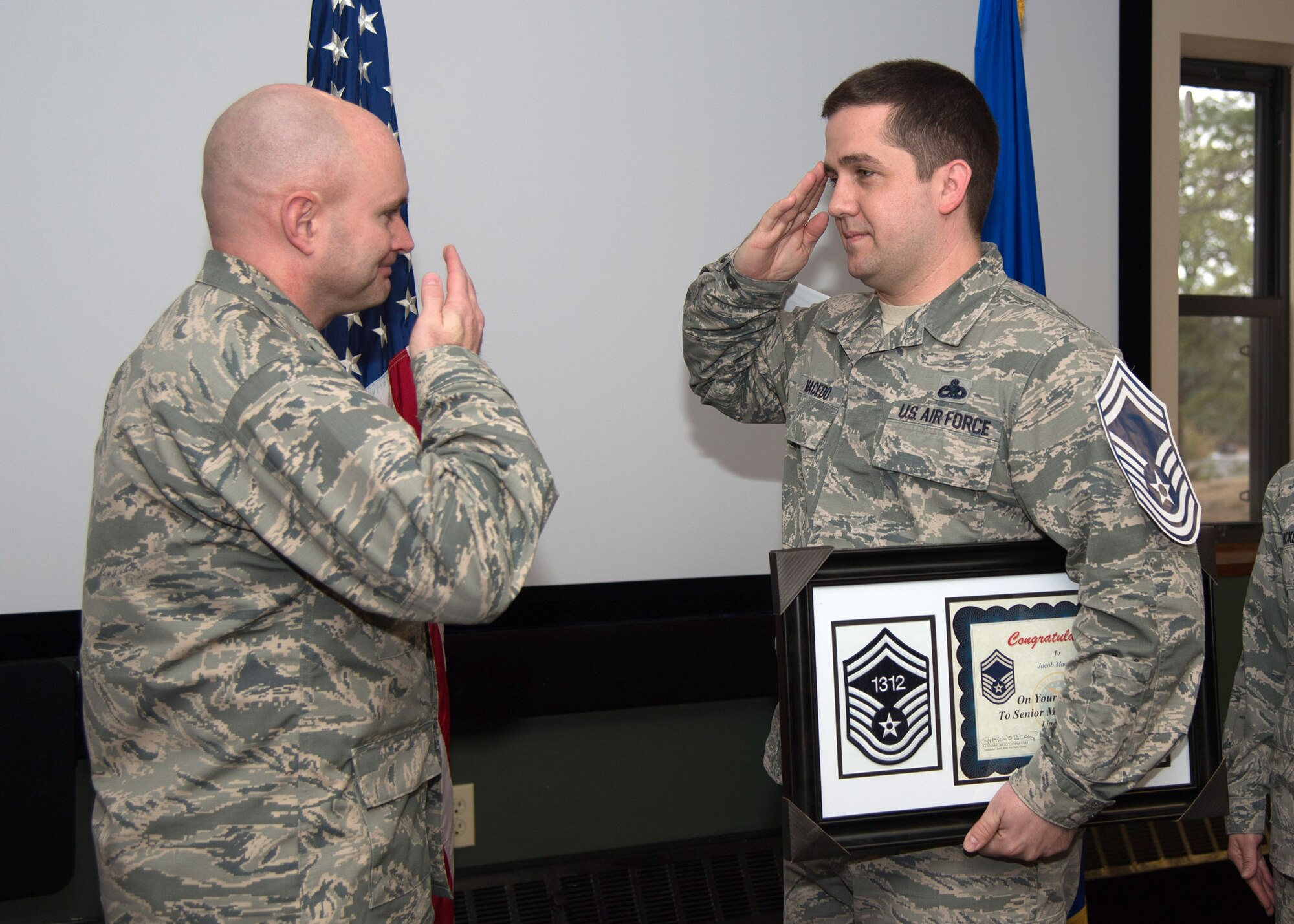 Master Sgt. Jacob Macedo, Airborne Warning and Control System Operational Capabilities Branch logistics superintendent, salutes Col. David R. Dunklee, installation commander, during an E-8 recognition celebration at the Minuteman Commons March 4. Macedo and Master Sgt. Toby James, 319th Recruiting Squadron first sergeant, were selected for promotion to senior master sergeant. The Air Force selected 1,467 master sergeants for promotion. (U.S. Air Force photo by Mark Herlihy)