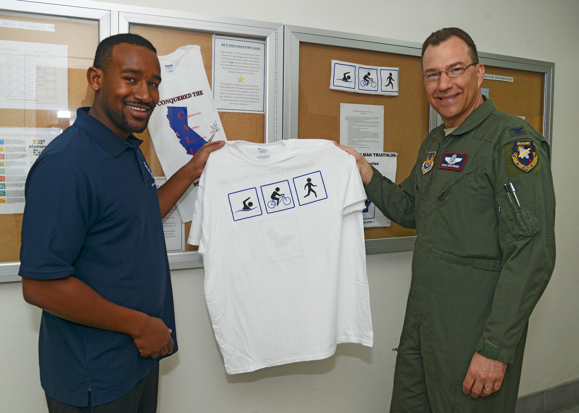 Col. David Radomski, 412th Test Wing vice commander, receives a Lazy Man Triathlon t-shirt from Andrew Neises, Rosburg Fitness Center, Feb. 7. The colonel completed the Lazy Man Triathlon by running, swimming and biking around Edwards, achieving the triathlon goals, which are four times the Ironman Triathlon distances. Just done at his own pace. (U.S. Air Force photo by Kenji Thuloweit)