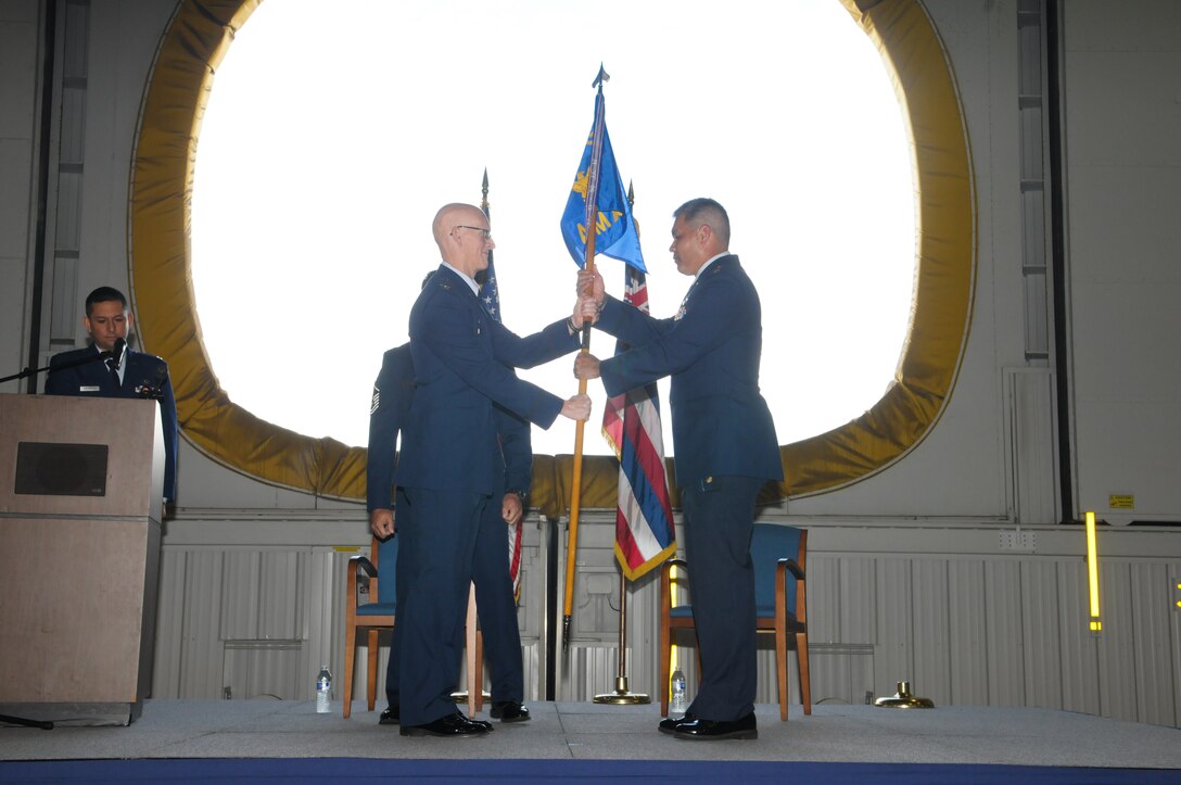 U.S. Air Force Col. Joseph Harris, 154th Maintenance Group commander hands the 154th Aircraft Maintenance Squadron guidon to U.S. Air Force Maj. Kimo Lowe during an assumption of command ceremony at Joint Base Pearl Harbor-Hickam, Feb. 21. 2016. Lowe accepted command of the Hawaii Air National Guard squadron tasked with helping in the maintenance of HIANG F-22 Raptors, KC-135 Stratotankers, and C-17 Globemaster aircraft. (U.S. Air National Guard photo by Airman 1st Class Robert Cabuco/released)